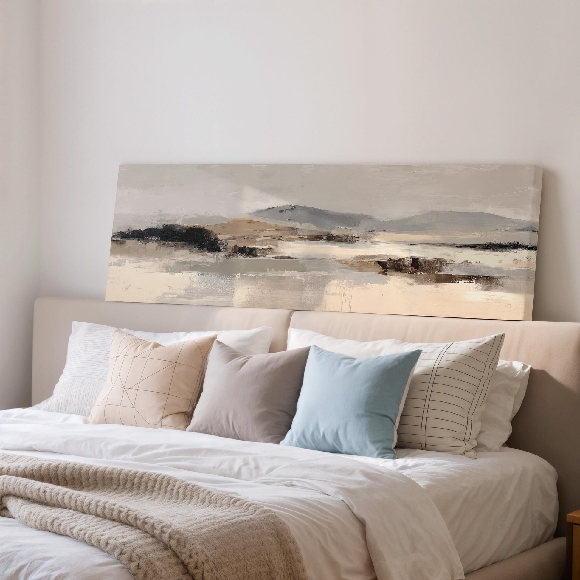a large painting of a landscape hanging above a bed with white bedding and various pillows.