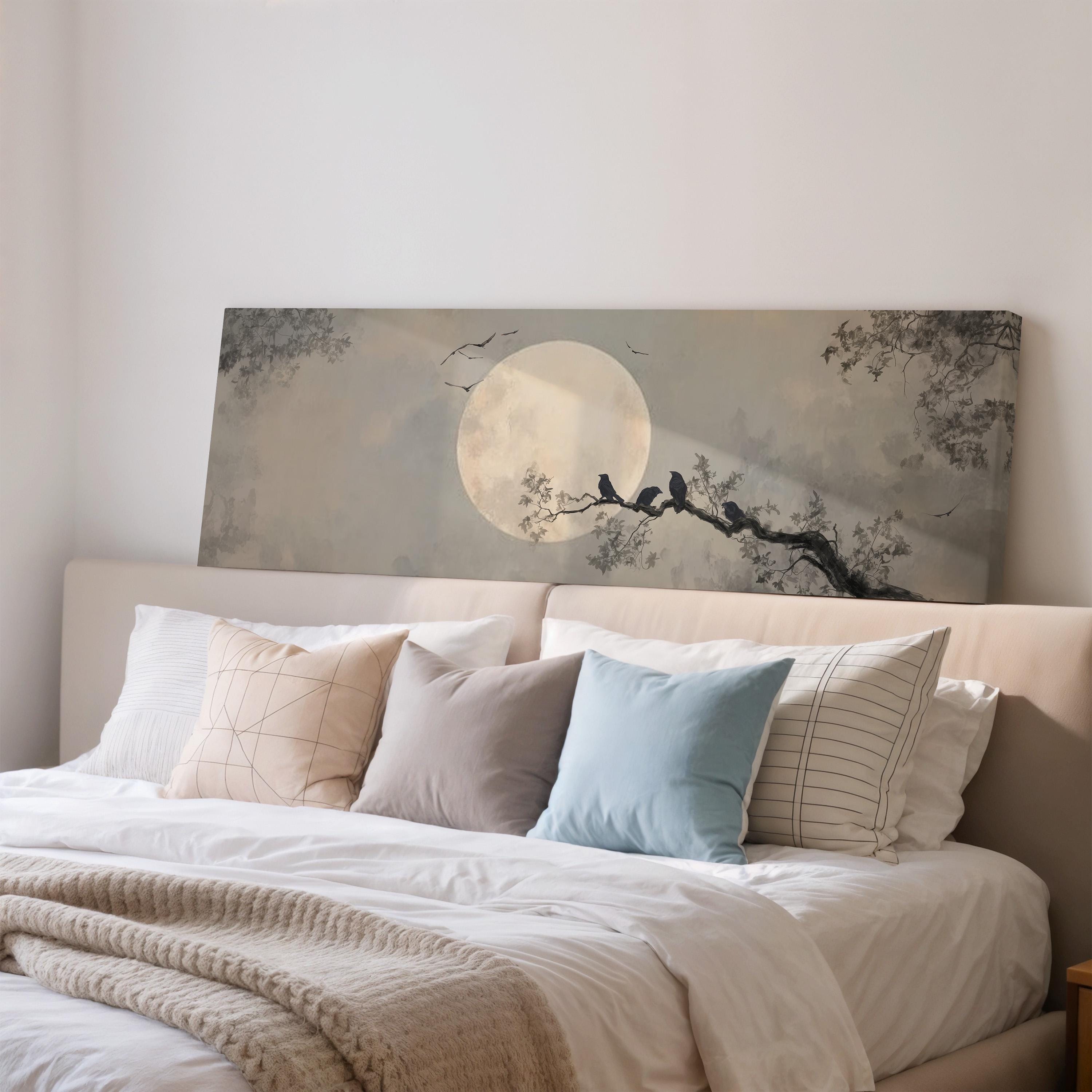 a serene bedroom scene with a large bed adorned with white linens and a blue pillow. Above the bed, there is a large canvas print depicting a moonlit tree with birds perched on its branches.