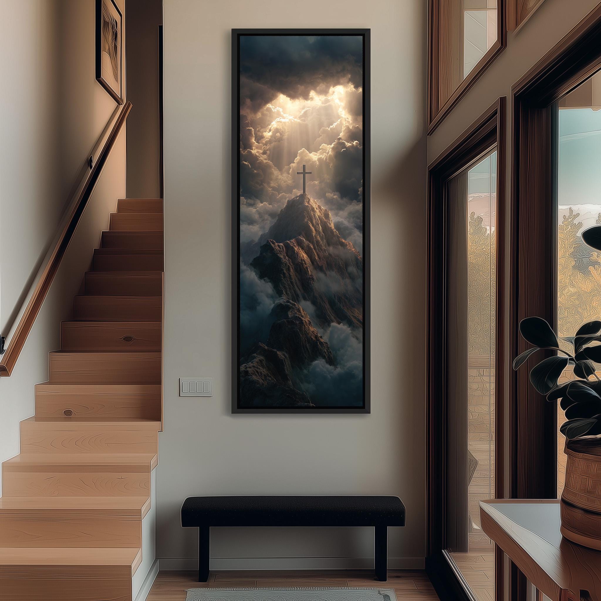 a serene indoor setting with a large framed painting of a mountain landscape hanging on the wall, featuring a cross and clouds. The painting is positioned above a black bench, which is situated in front of a window. The overall scene conveys a sense of tranquility and spiritual contemplation.