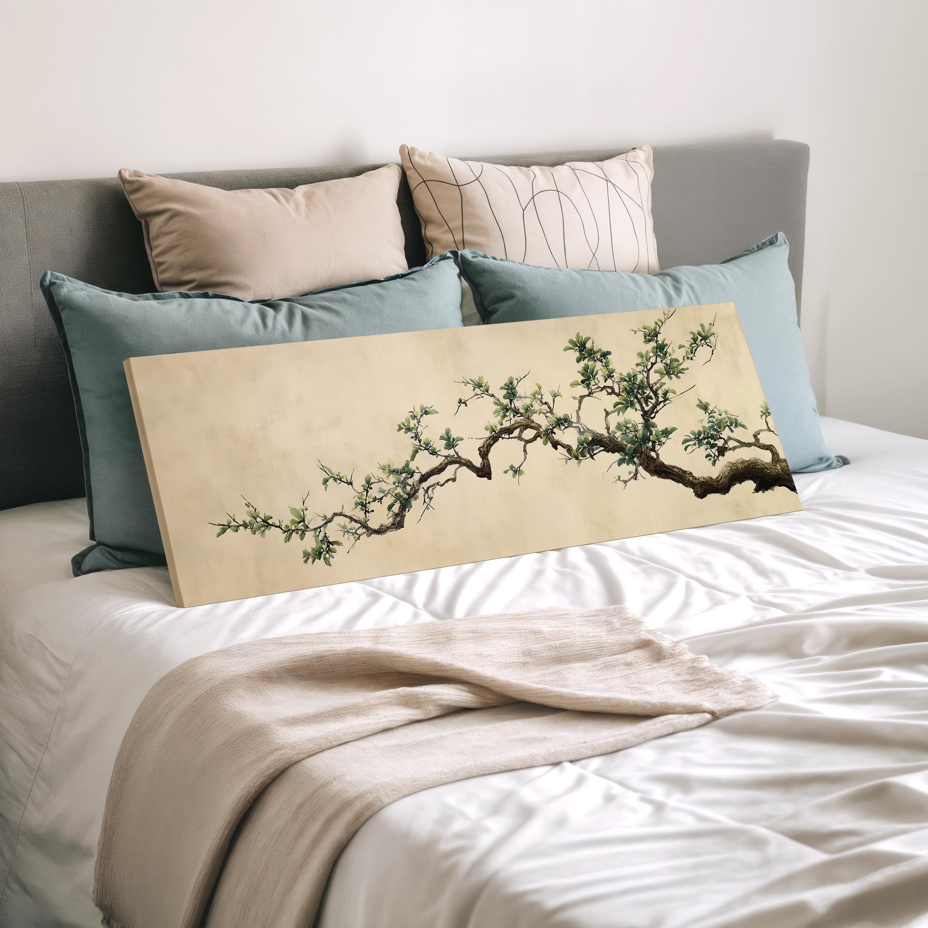a bedroom with a bed and a large painting of a tree branch on it. The bed is covered with white sheets and has several pillows on it. The painting is placed on the bed, and it appears to be a large canvas print depicting a tree branch with green leaves.