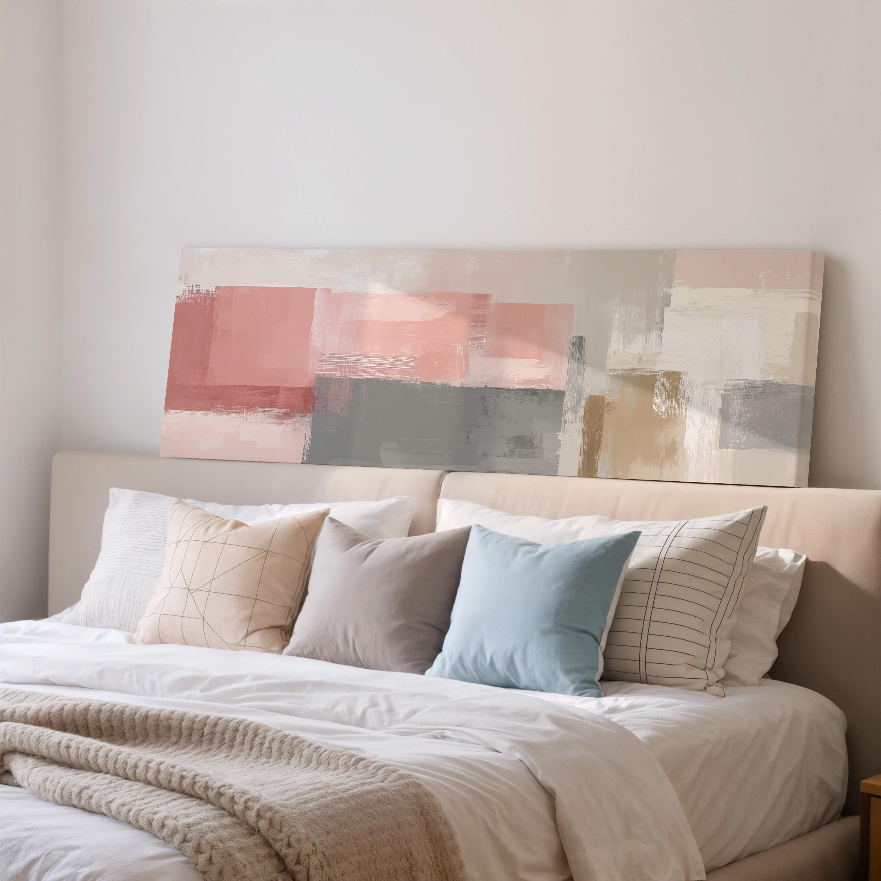 a well-made bed with a white comforter and various pillows in different colors and patterns, including a large abstract painting above the bed.