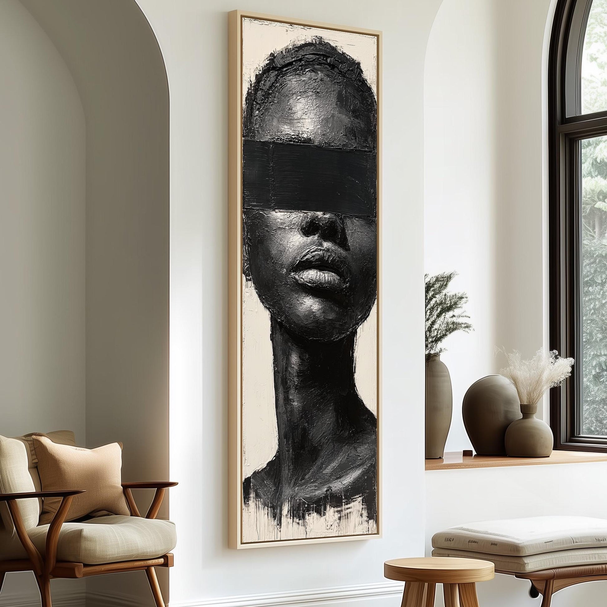 a large black and white portrait of a woman's face hanging on a wall, with a wooden chair and a small table in the foreground.