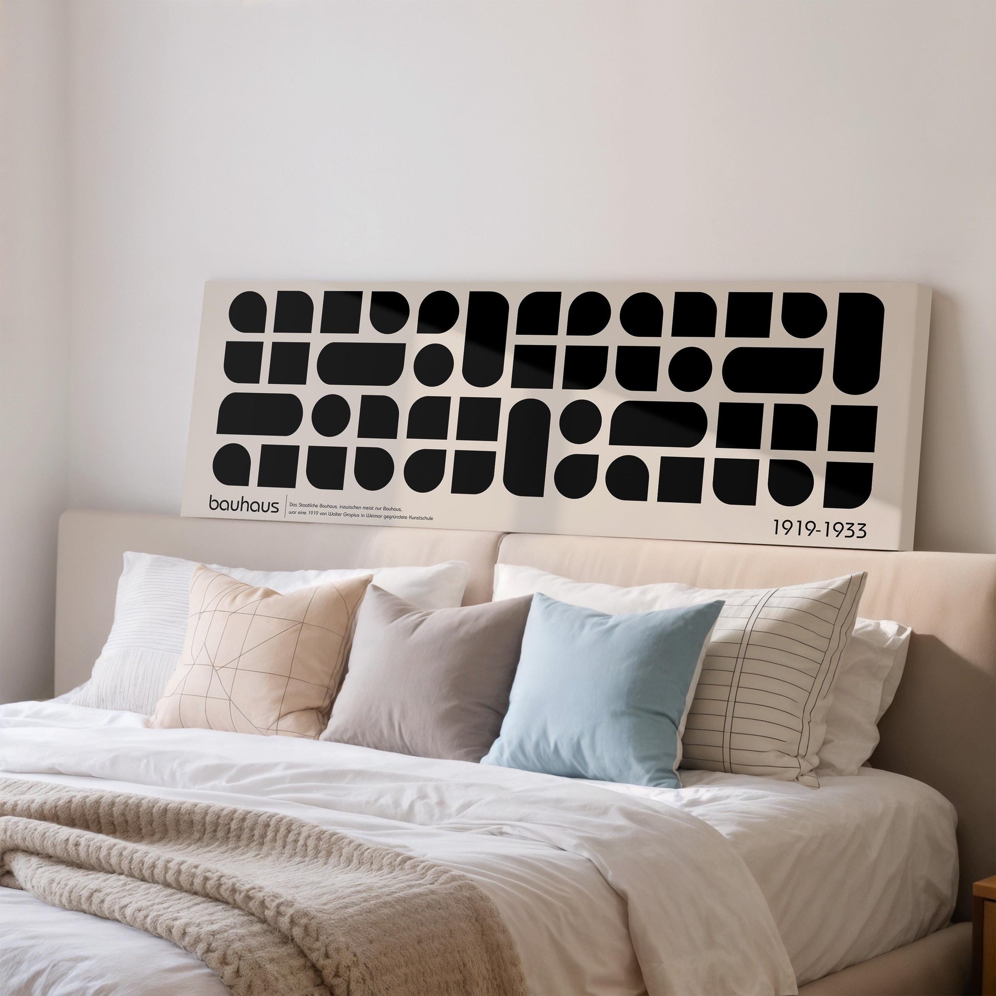a large bed with a white headboard and a black and white abstract artwork displayed above it.