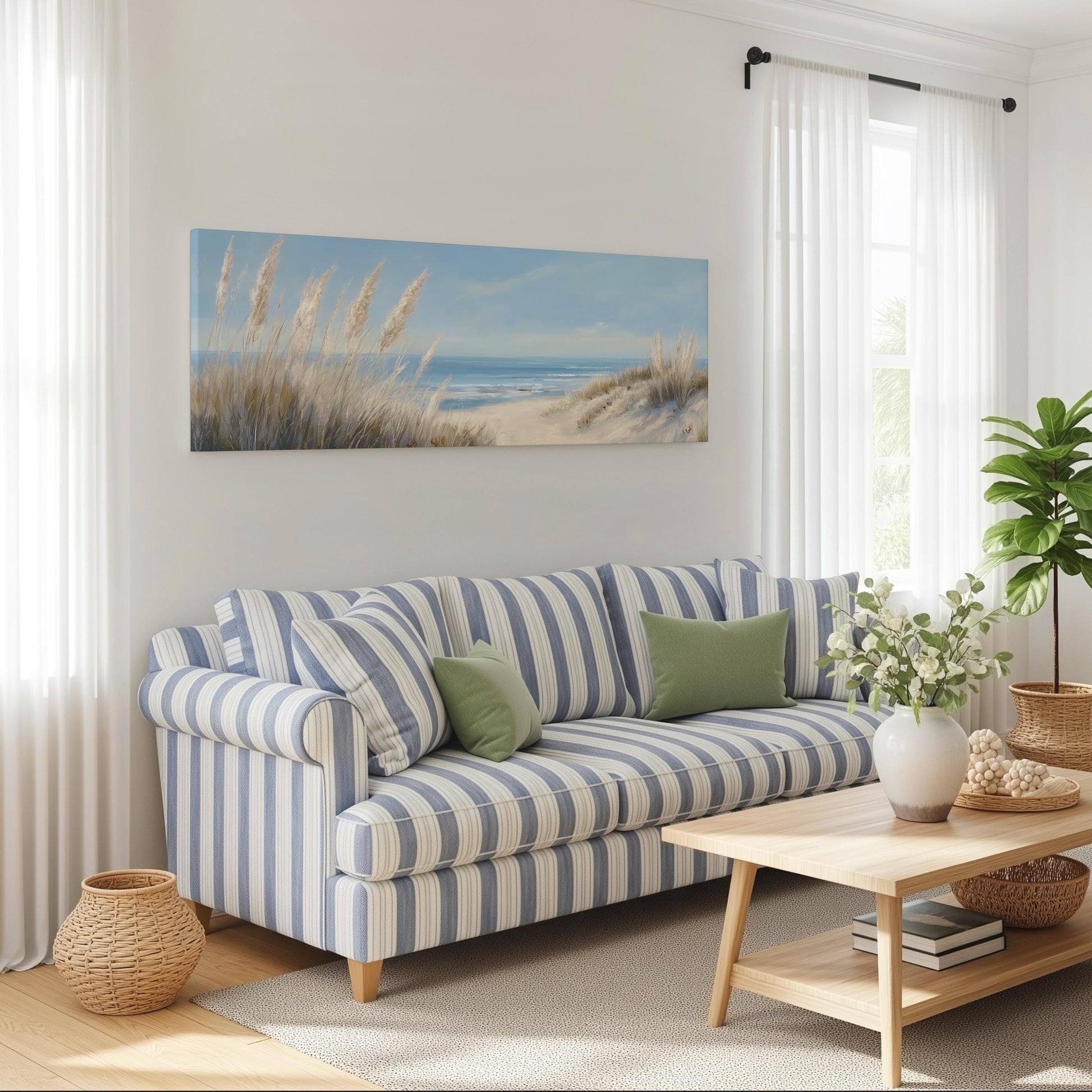 a cozy living room with a striped blue and white sofa, a wooden coffee table, and a large window with white curtains. Above the sofa, there is a painting of a beach scene with tall grasses and a sandy beach.