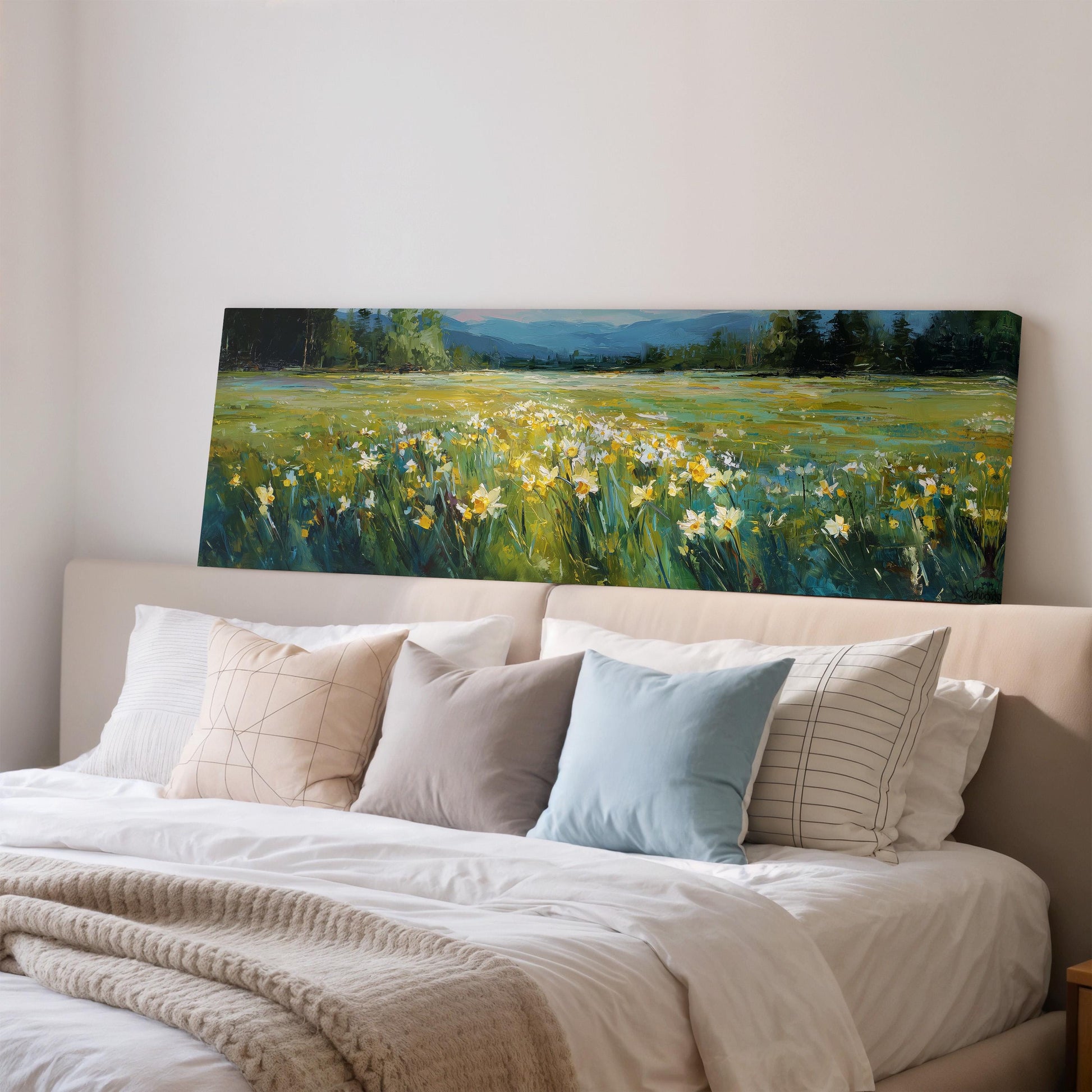 a large painting of a field of flowers hanging on a wall above a bed with white pillows and a gray blanket.