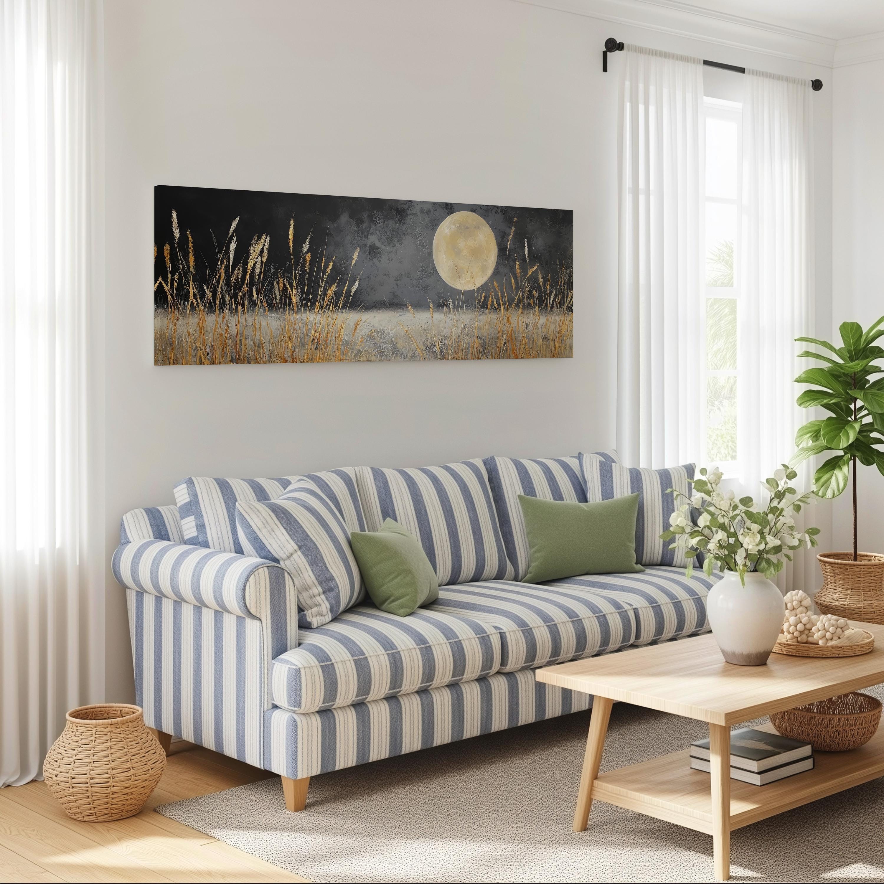 a cozy living room with a striped blue and white sofa, a wooden coffee table, and a large painting of a field with a full moon in the background.