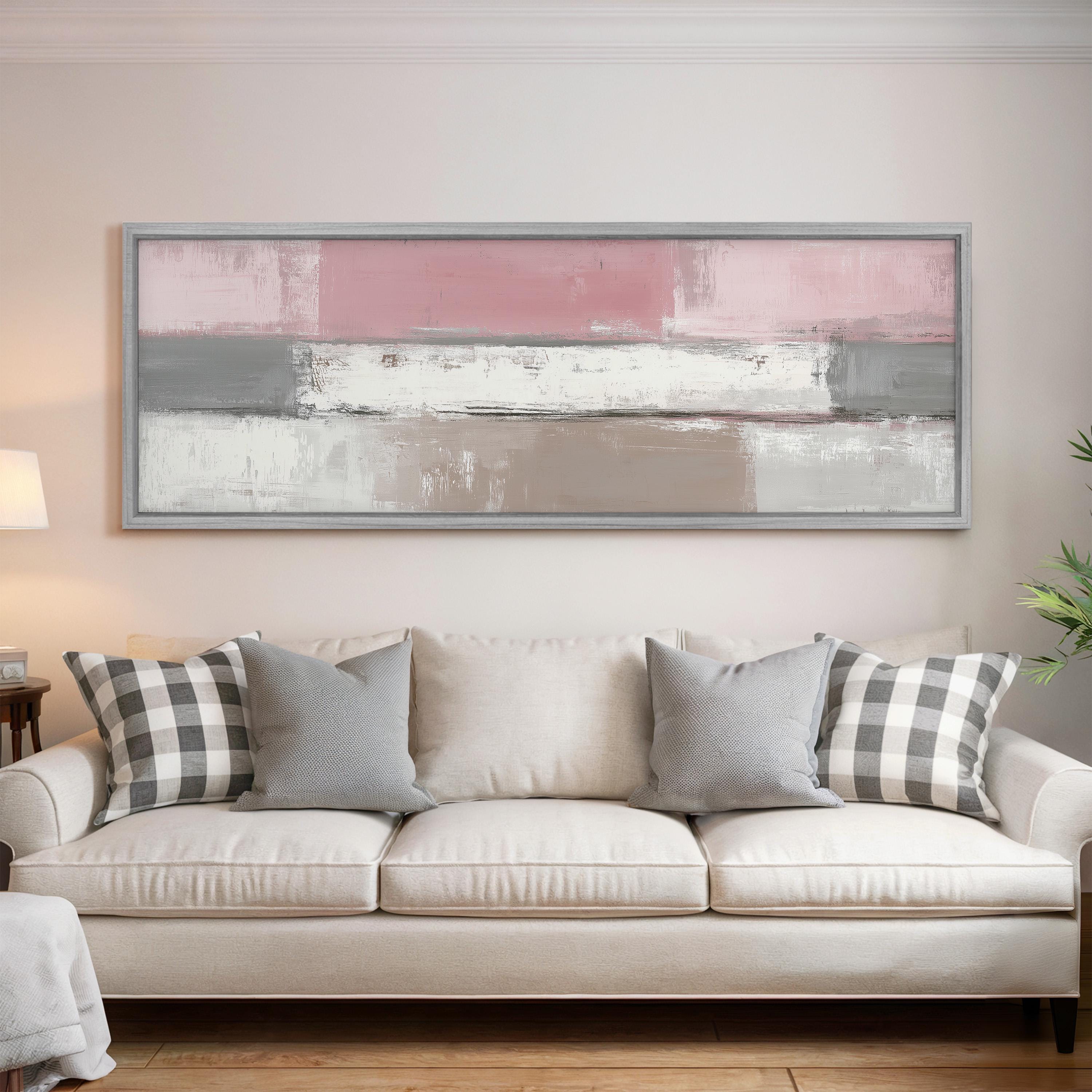 a living room with a white sofa adorned with gray and black plaid throw pillows. Above the sofa, there is a large abstract painting in shades of pink and white.