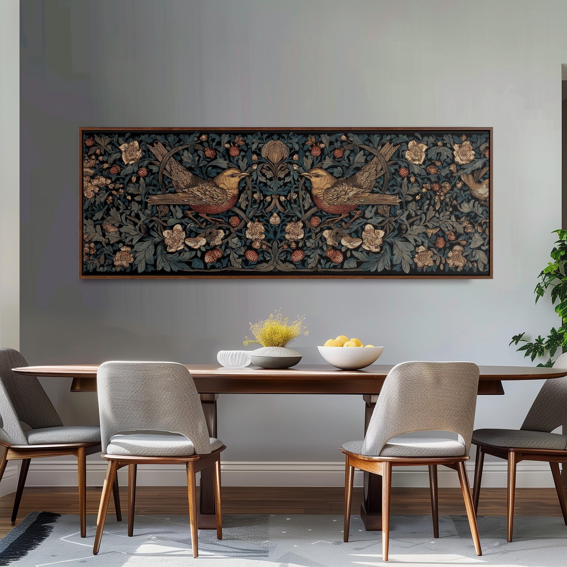 a dining room with a wooden table and four chairs. Above the table, there is a large framed artwork depicting two birds on a floral background. The table is set with a bowl of fruit and a vase of flowers, creating a cozy and inviting atmosphere.