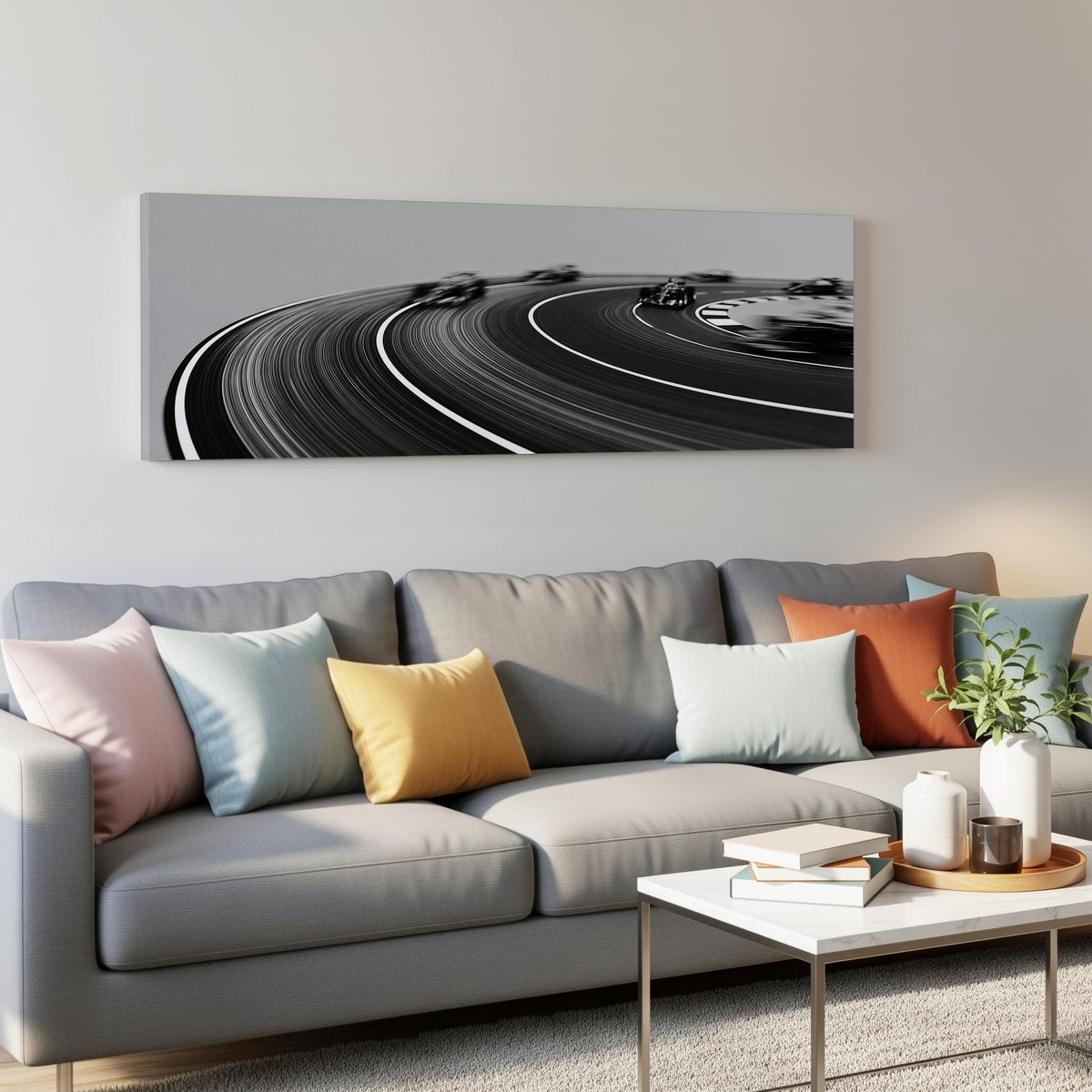 Race cars sweeping around a curve in black and white panoramic canvas print above a grey sofa in a living room