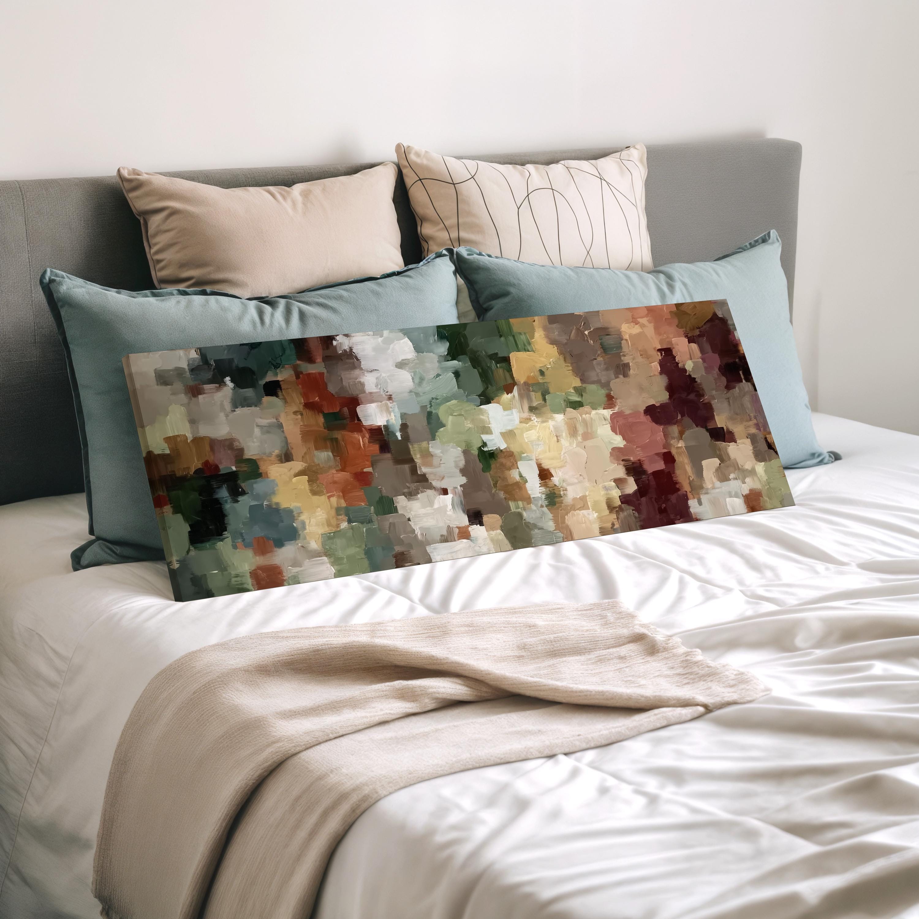 a bedroom with a bed covered in white sheets and a large abstract painting resting on top of the bed.