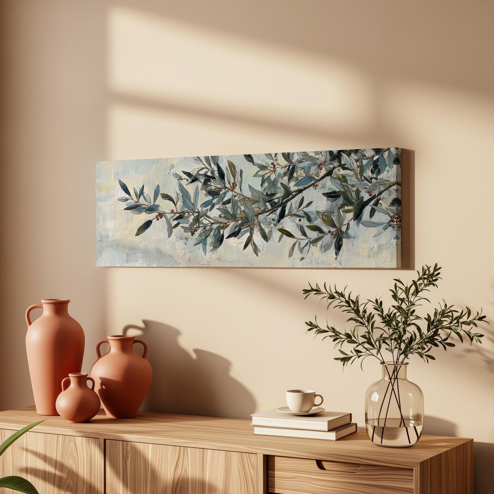 a wooden cabinet with a painting of a branch of green leaves hanging on the wall above it. The cabinet also has three orange vases and a glass vase with a plant on top of it.