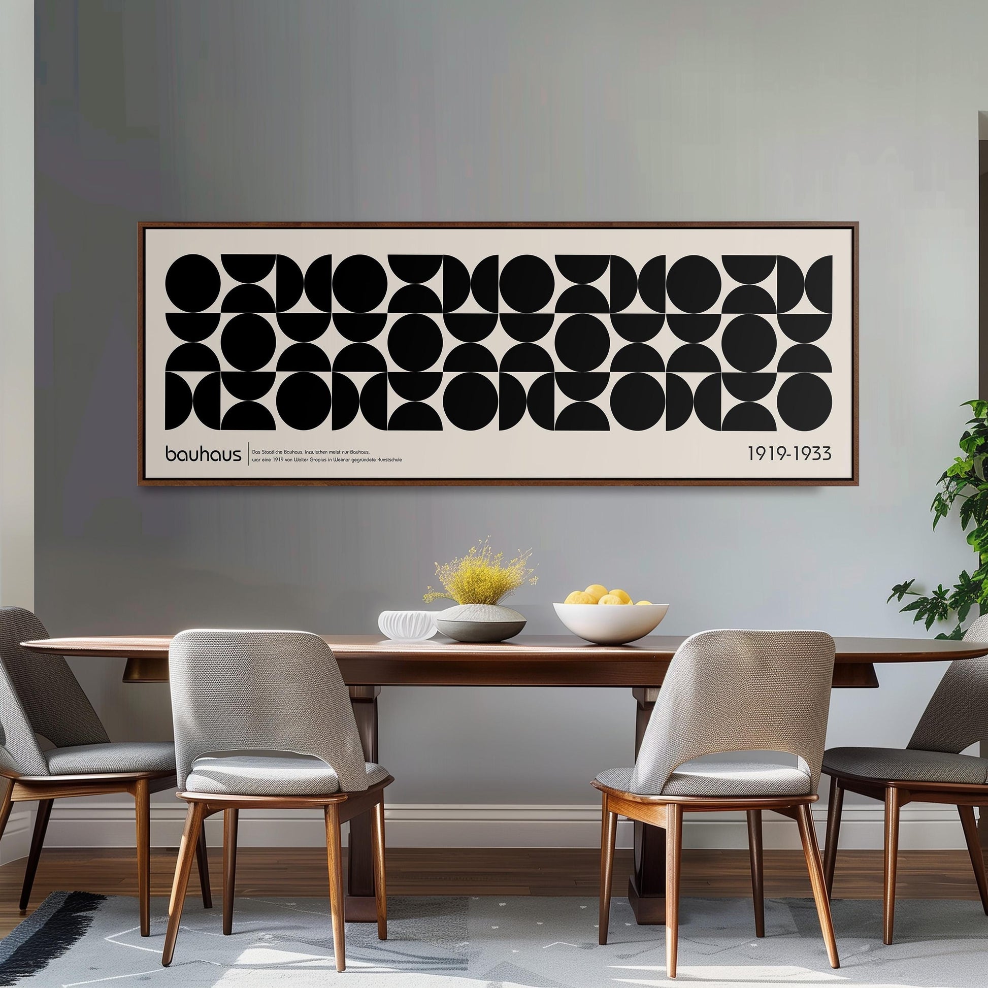 a dining room with a wooden table and four chairs, a large abstract art piece hanging on the wall above the table, and a bowl of fruit on the table.