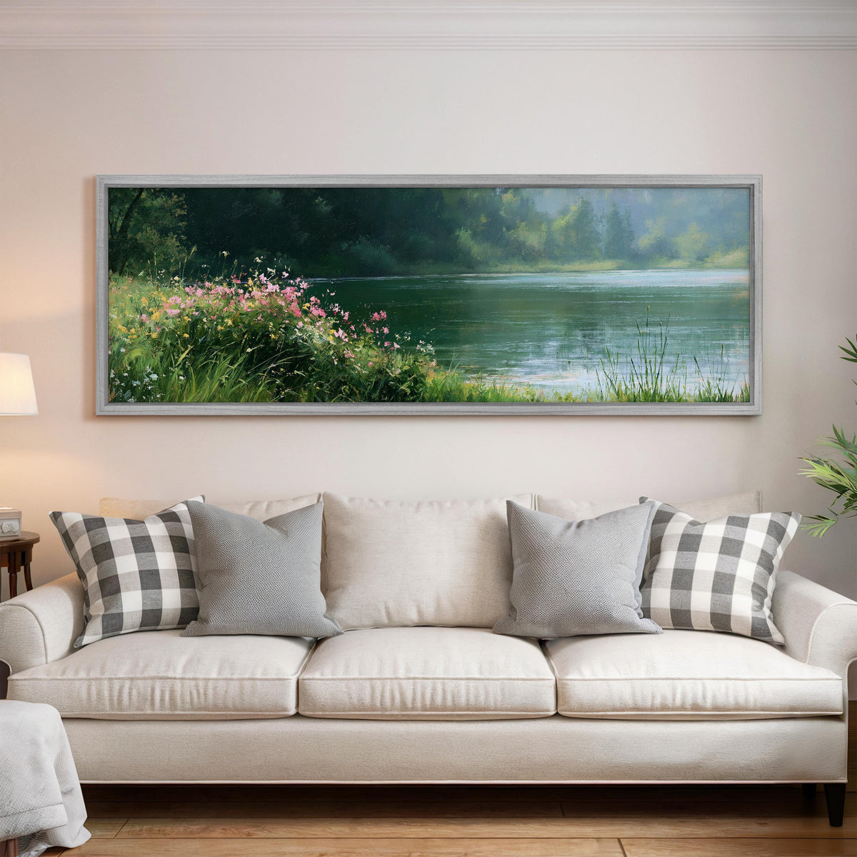 Pink wildflowers on a green lakeshore panoramic canvas print above a white sofa in a bright living room