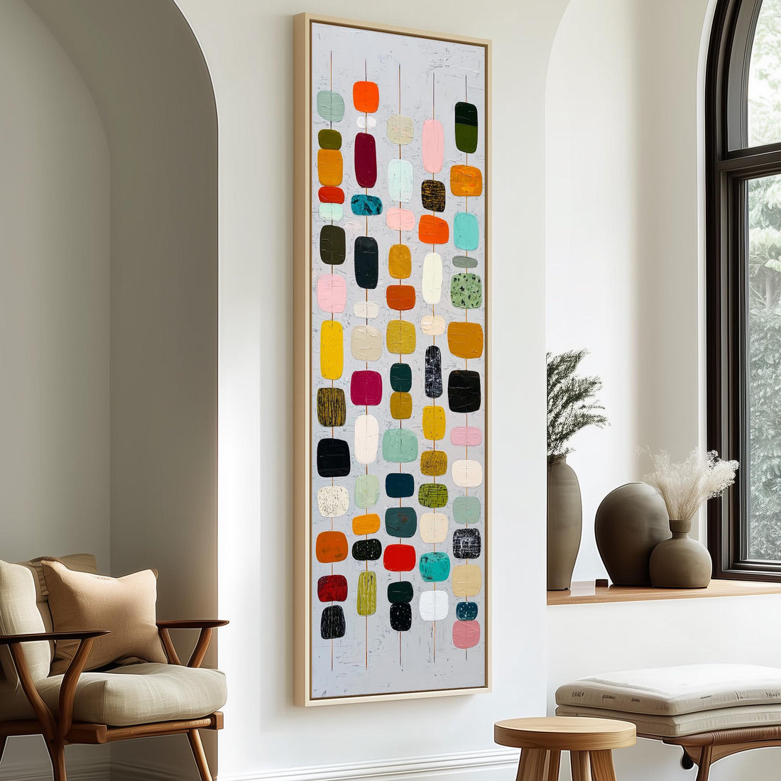 a large abstract painting hanging on a wall, with a wooden cabinet and a vase of flowers to the right of the painting.