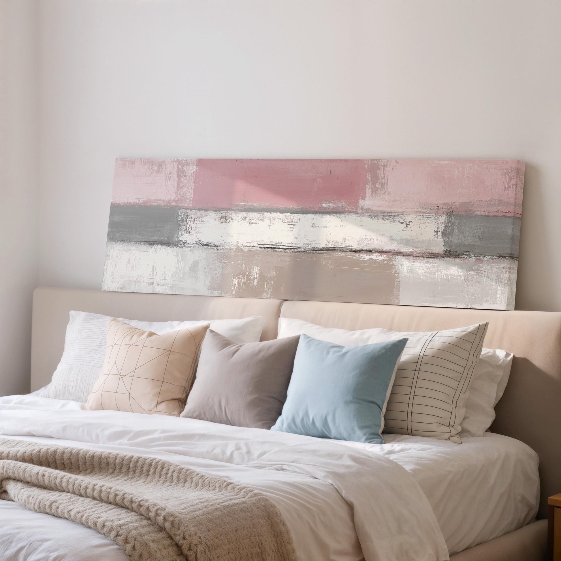a cozy bedroom with a large bed adorned with a white comforter and a variety of colorful pillows. Above the bed, there is a large abstract painting in shades of pink and gray.
