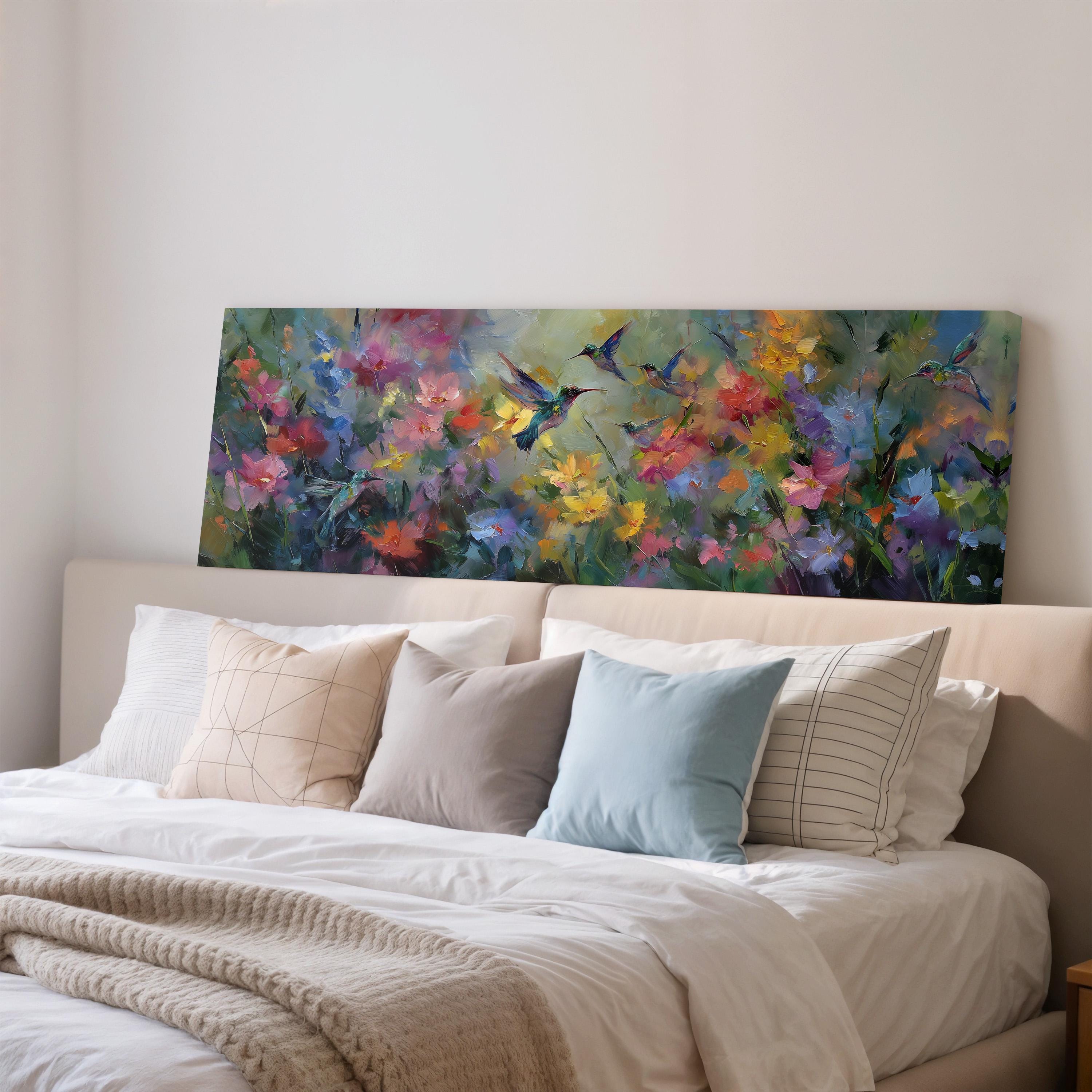 a large, colorful painting of flowers hanging above a bed with white pillows and a gray blanket.