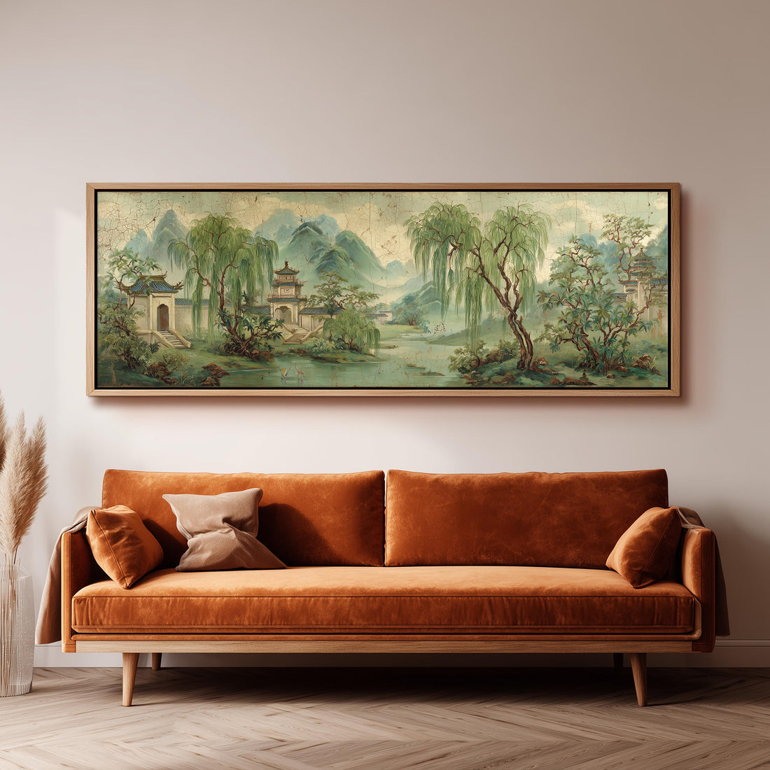 a large, framed painting of a serene landscape hanging on a wall above a brown sofa with orange cushions.