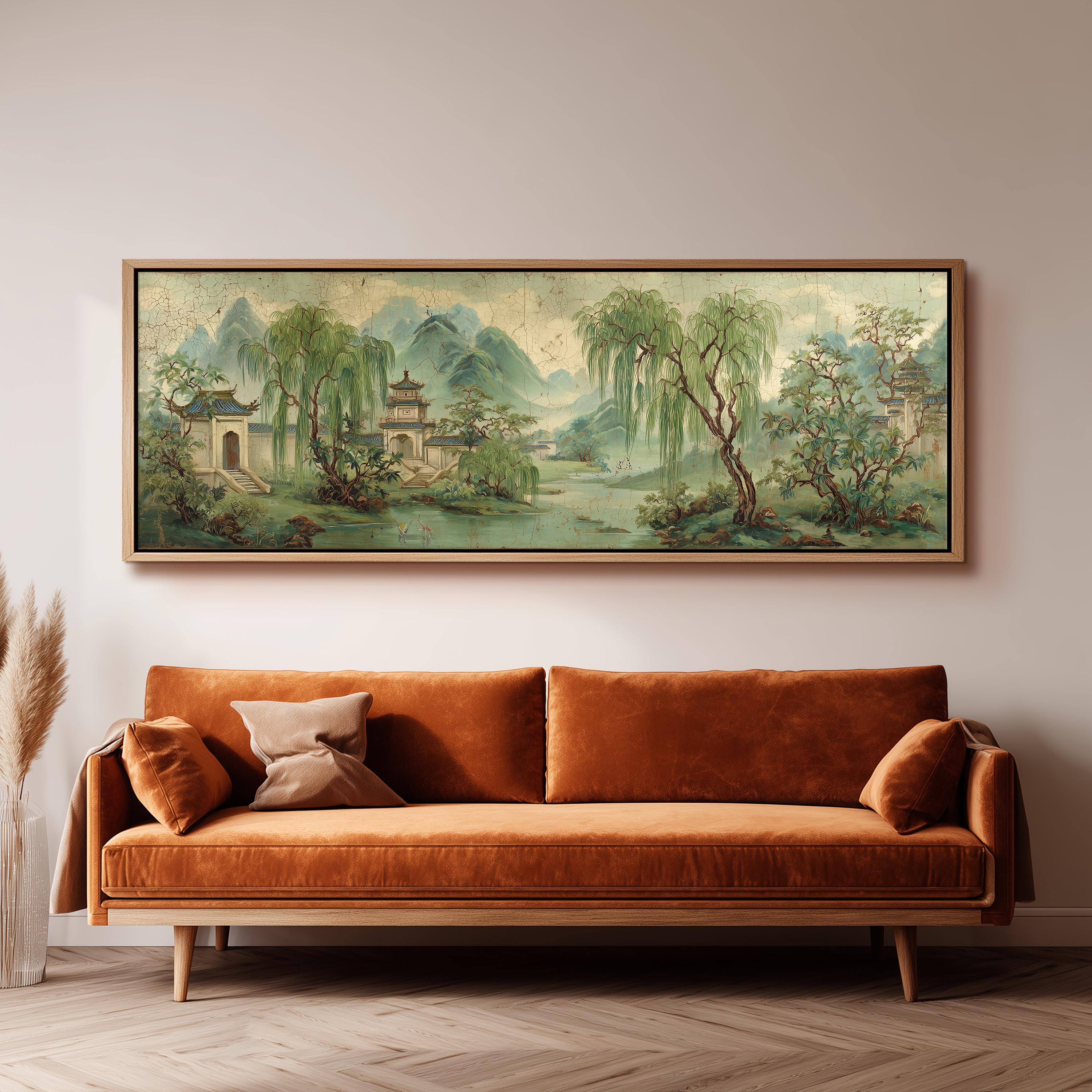 a large, framed painting of a serene landscape hanging on a wall above a brown sofa with orange cushions.