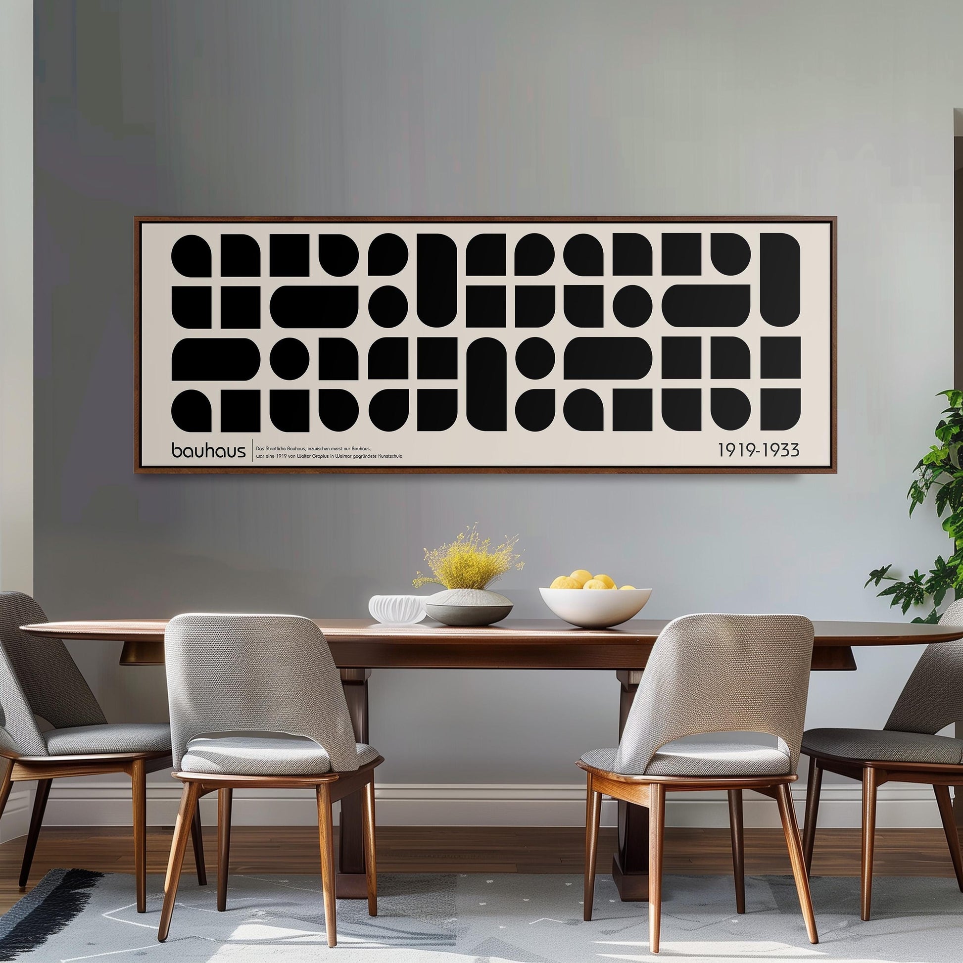 a dining room with a wooden table and four chairs. Above the table, there is a large black and white abstract artwork with a repeating pattern of circles and rectangles. The artwork is framed and hangs on the wall above the dining table.