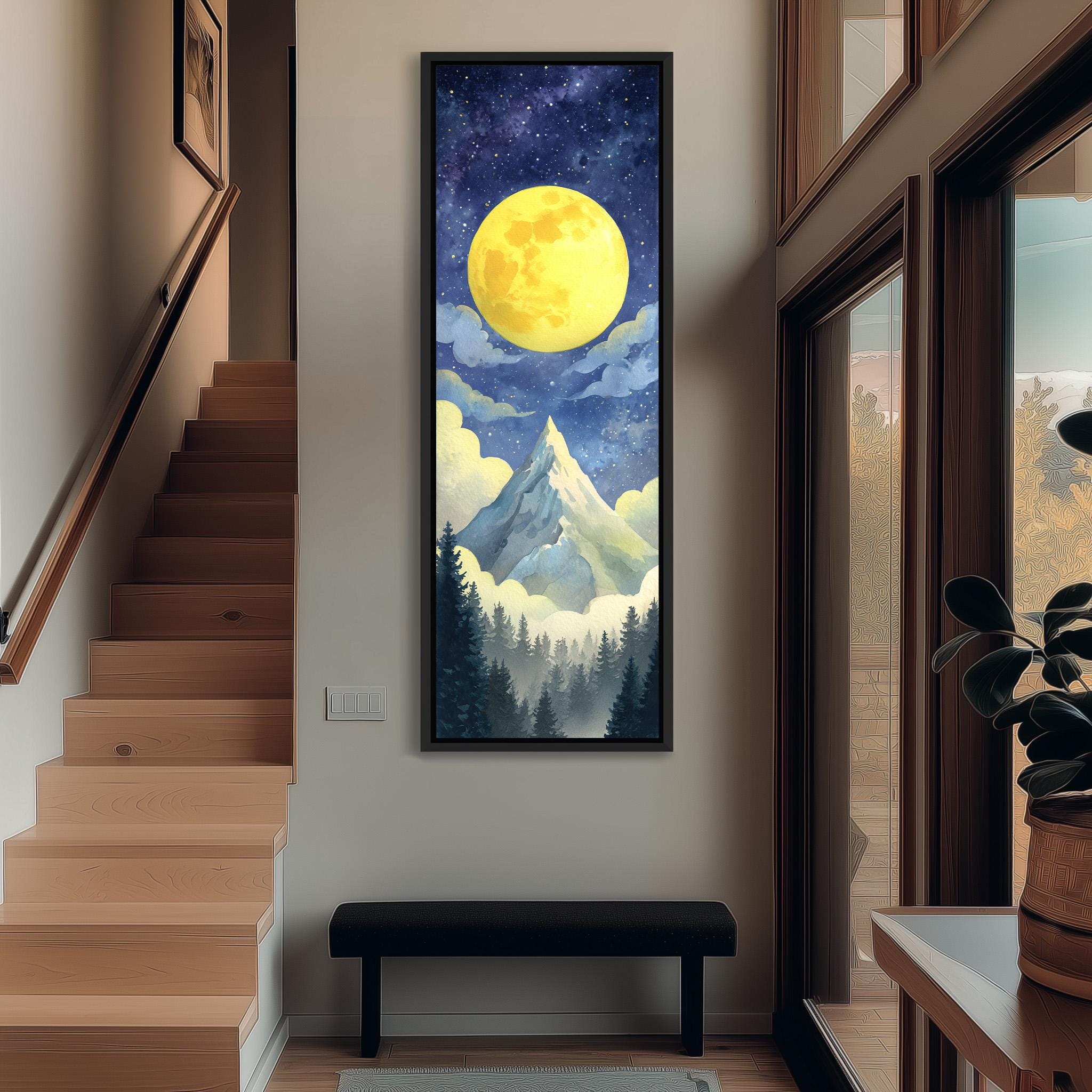 a large painting of a mountain landscape with a bright yellow moon in the night sky, surrounded by clouds and trees. The painting is hanging on a wall in a hallway, with a wooden staircase visible in the background.