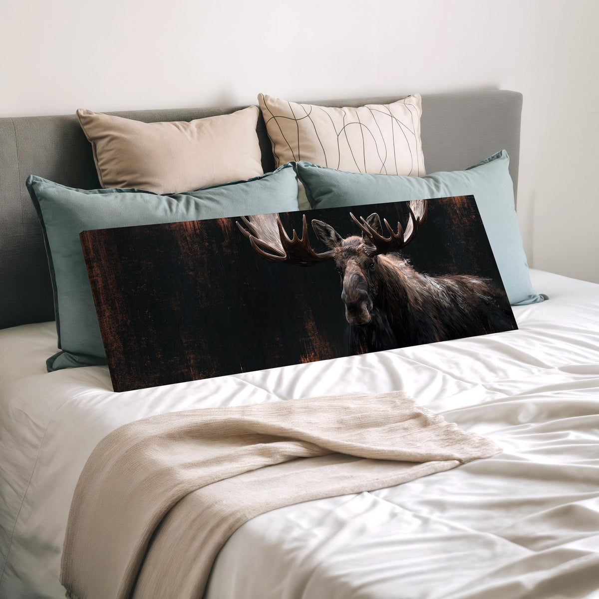 Dark moose portrait wide panoramic canvas print laid on a bed to show its size