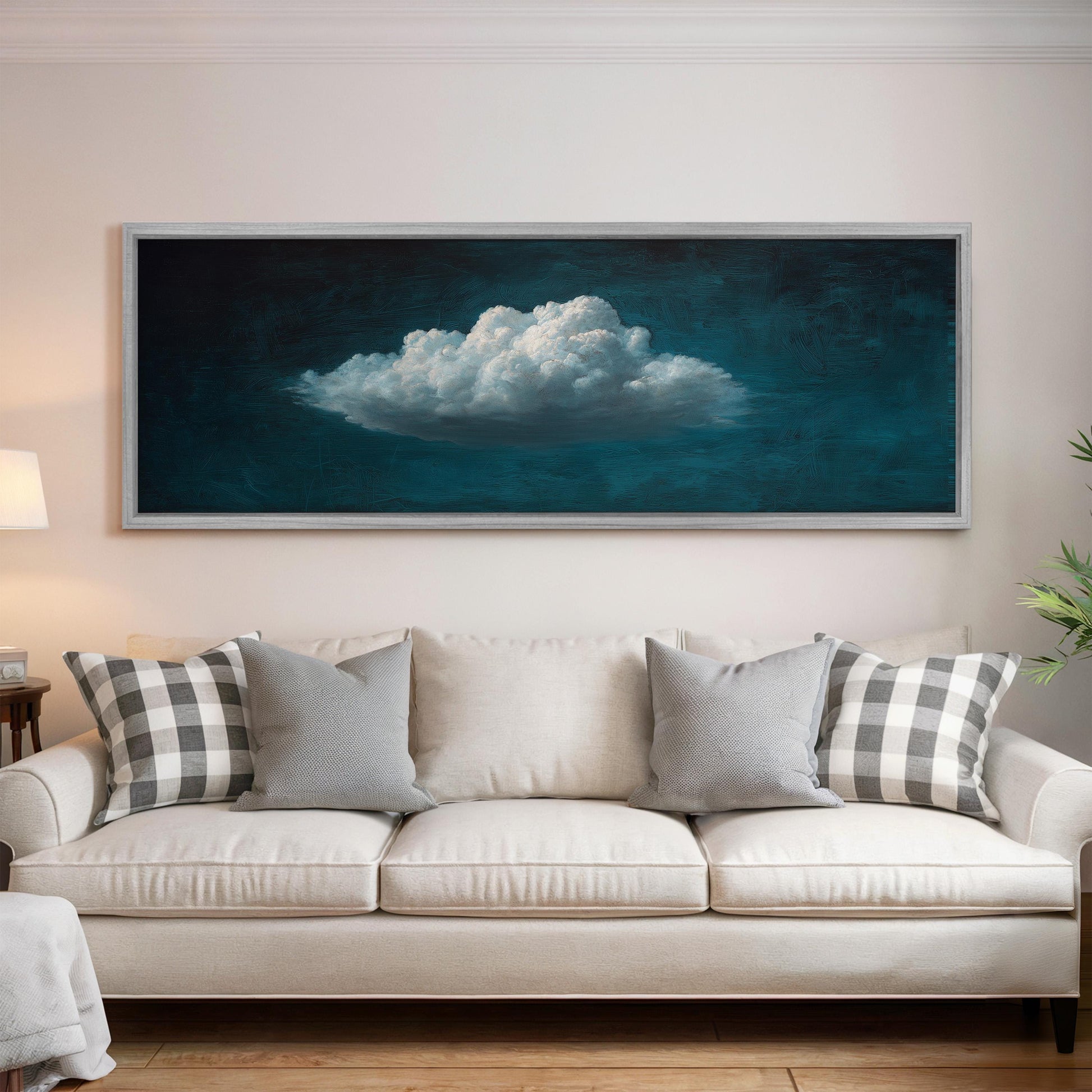 a large, framed painting of a cloud hanging on a wall above a white couch with gray and white plaid throw pillows.