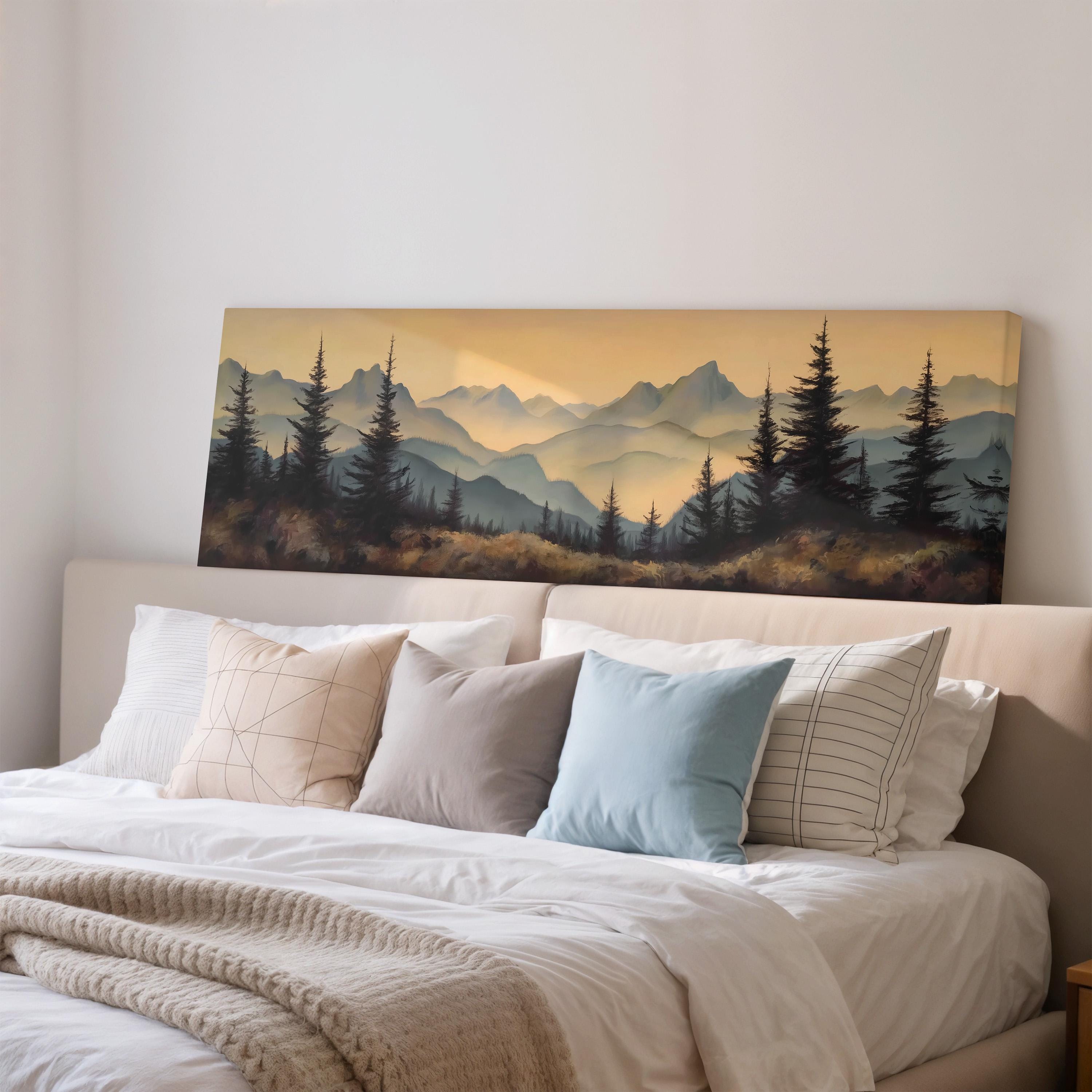 a large landscape painting hanging on a wall above a bed with white pillows and a gray blanket.
