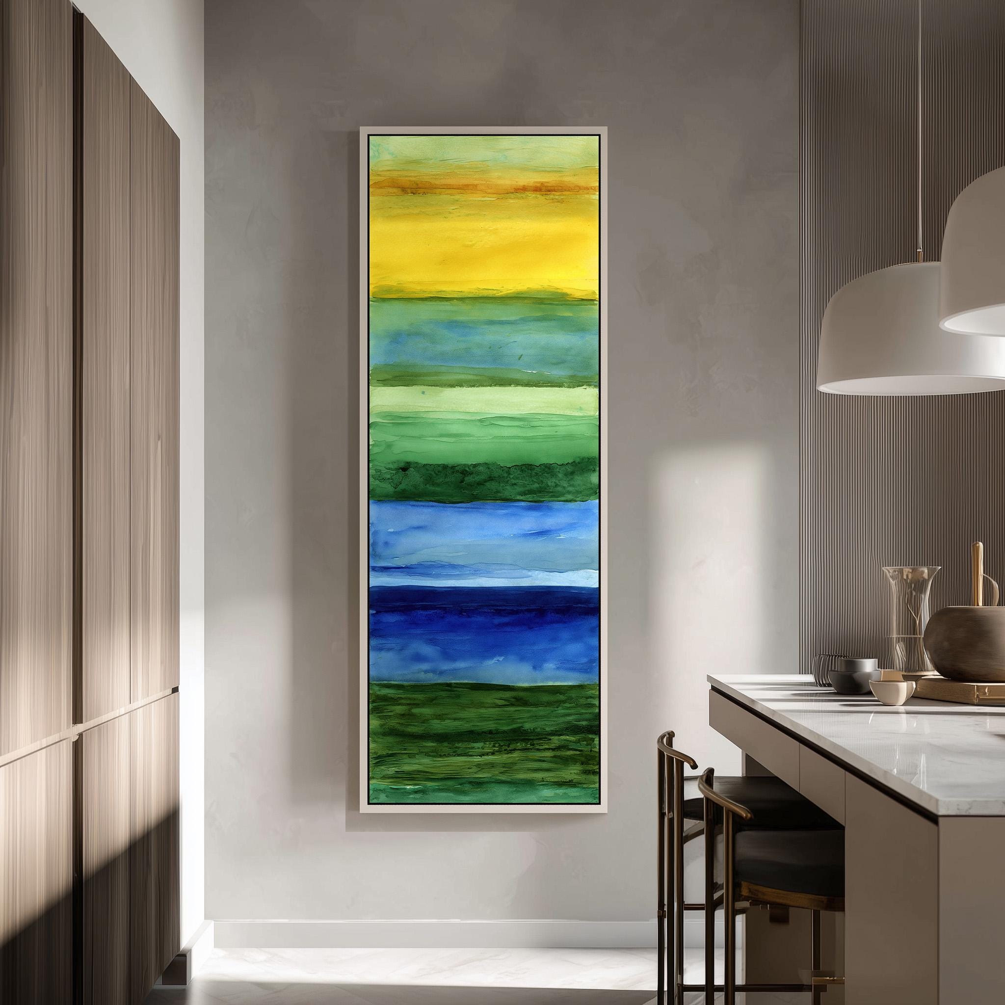 a modern kitchen with a large, colorful painting hanging on the wall above a counter. The painting depicts a vibrant rainbow-like scene with various shades of green, blue, and yellow. The kitchen has a clean, minimalist design with white cabinets and a white countertop. There are also some chairs and a vase visible in the room.
