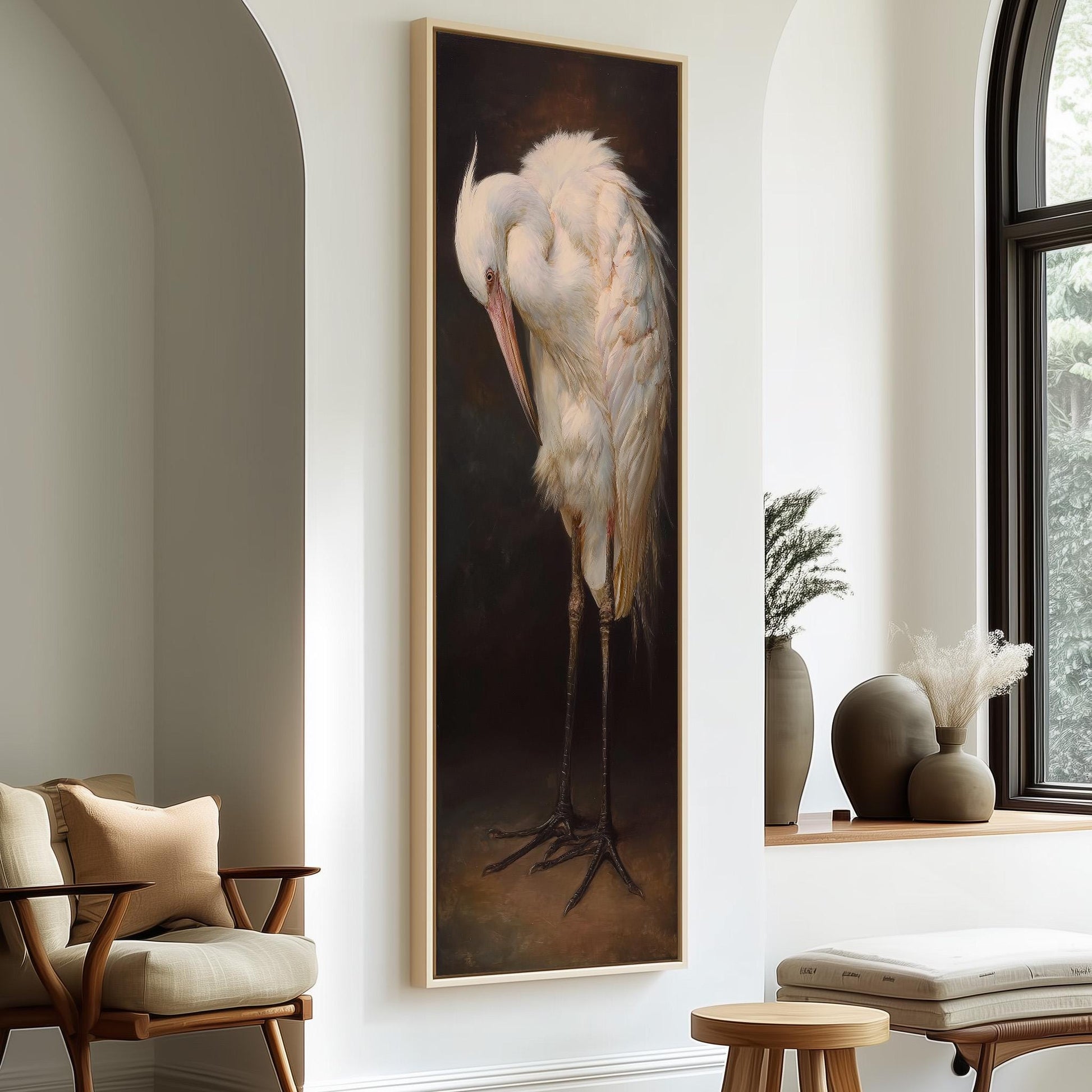 a large painting of a white heron standing on one leg, hanging on a wall in a room with a window and a wooden chair.