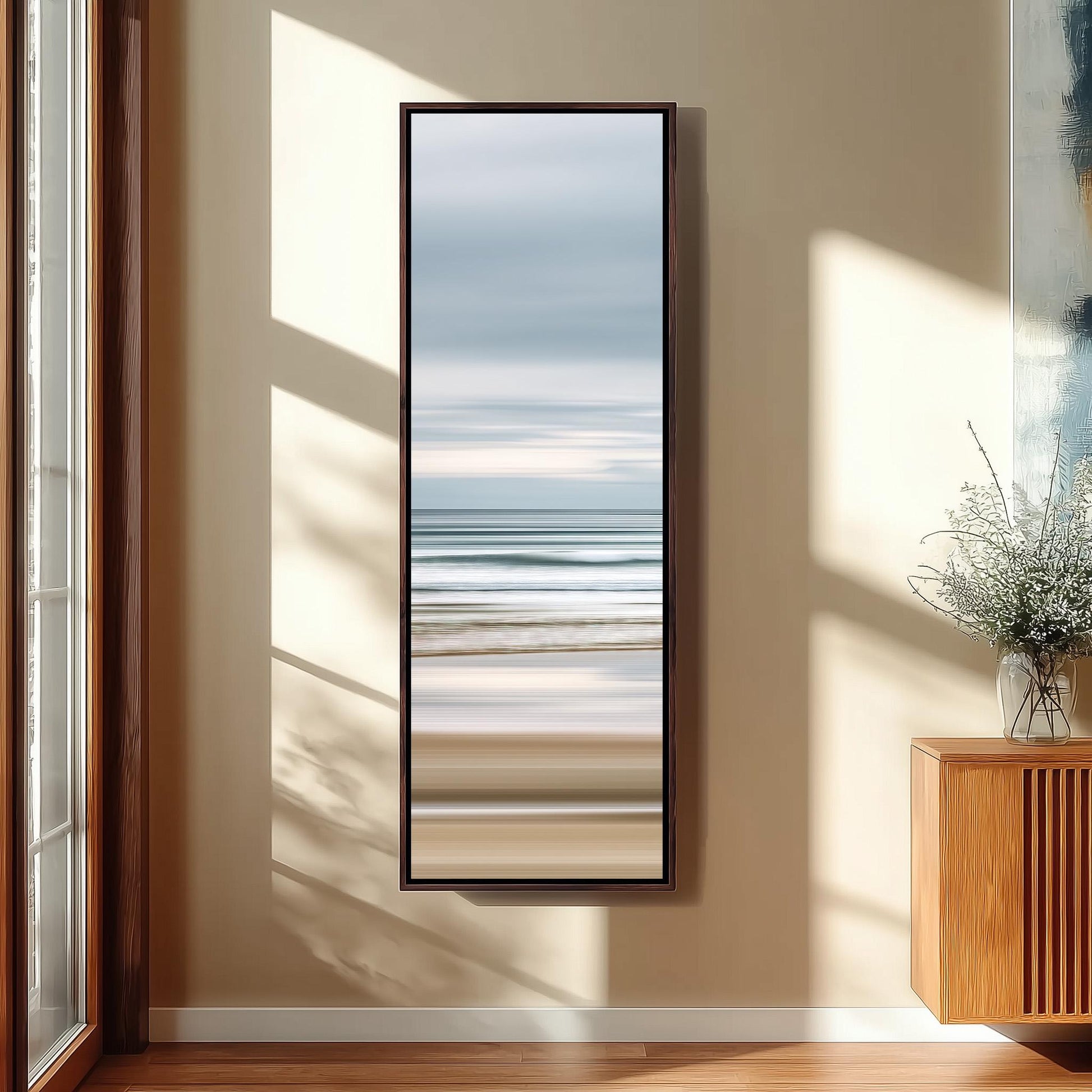 a large mirror hanging on a wall, reflecting a serene beach scene with a calm ocean and a clear sky.