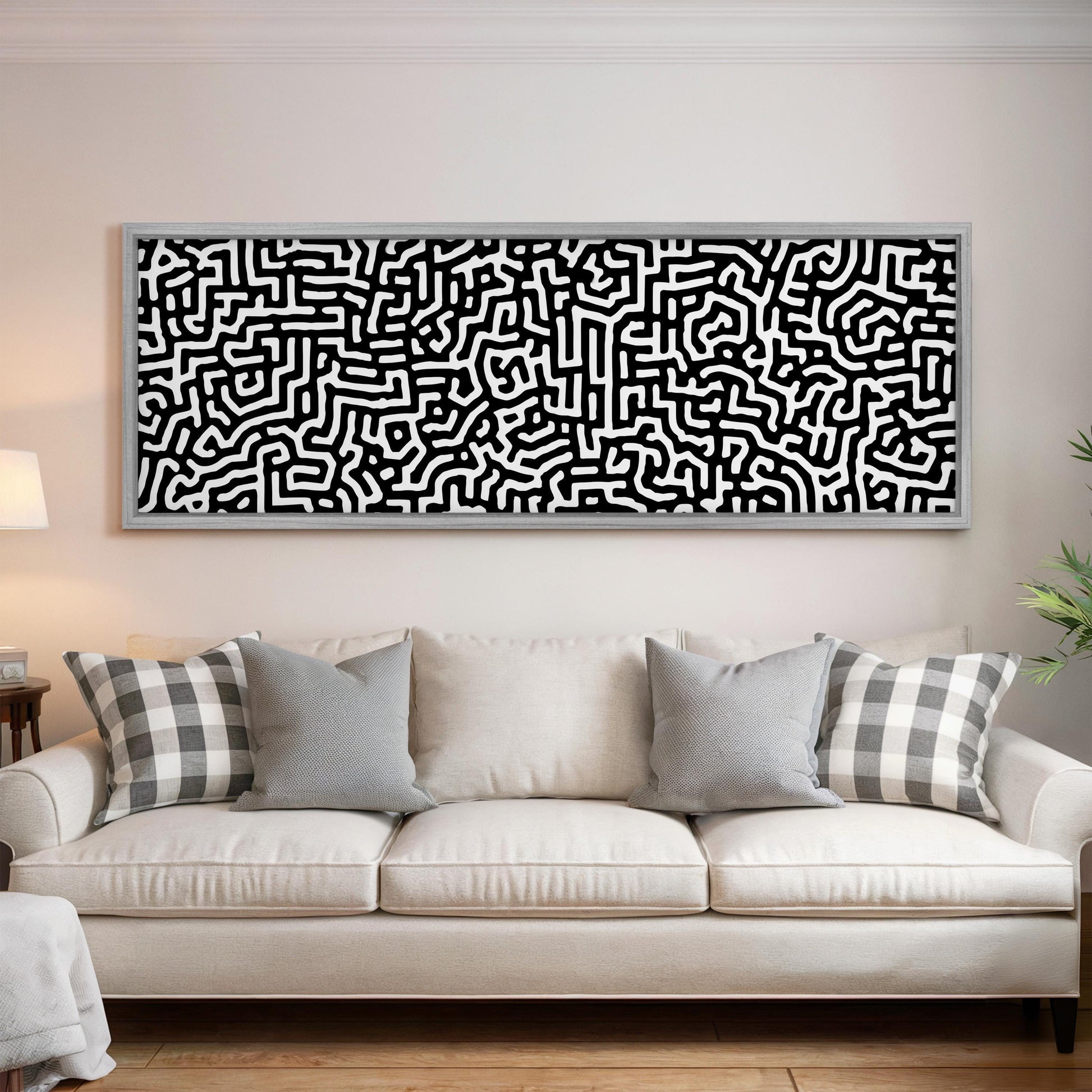 a large black and white abstract painting hanging on a wall above a white couch with gray and white throw pillows.