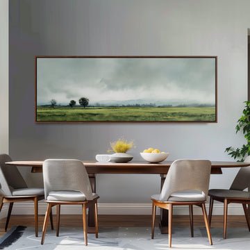 a dining room with a large painting of a field hanging on the wall above a wooden dining table with four chairs. The painting depicts a serene landscape with a cloudy sky and rolling hills.