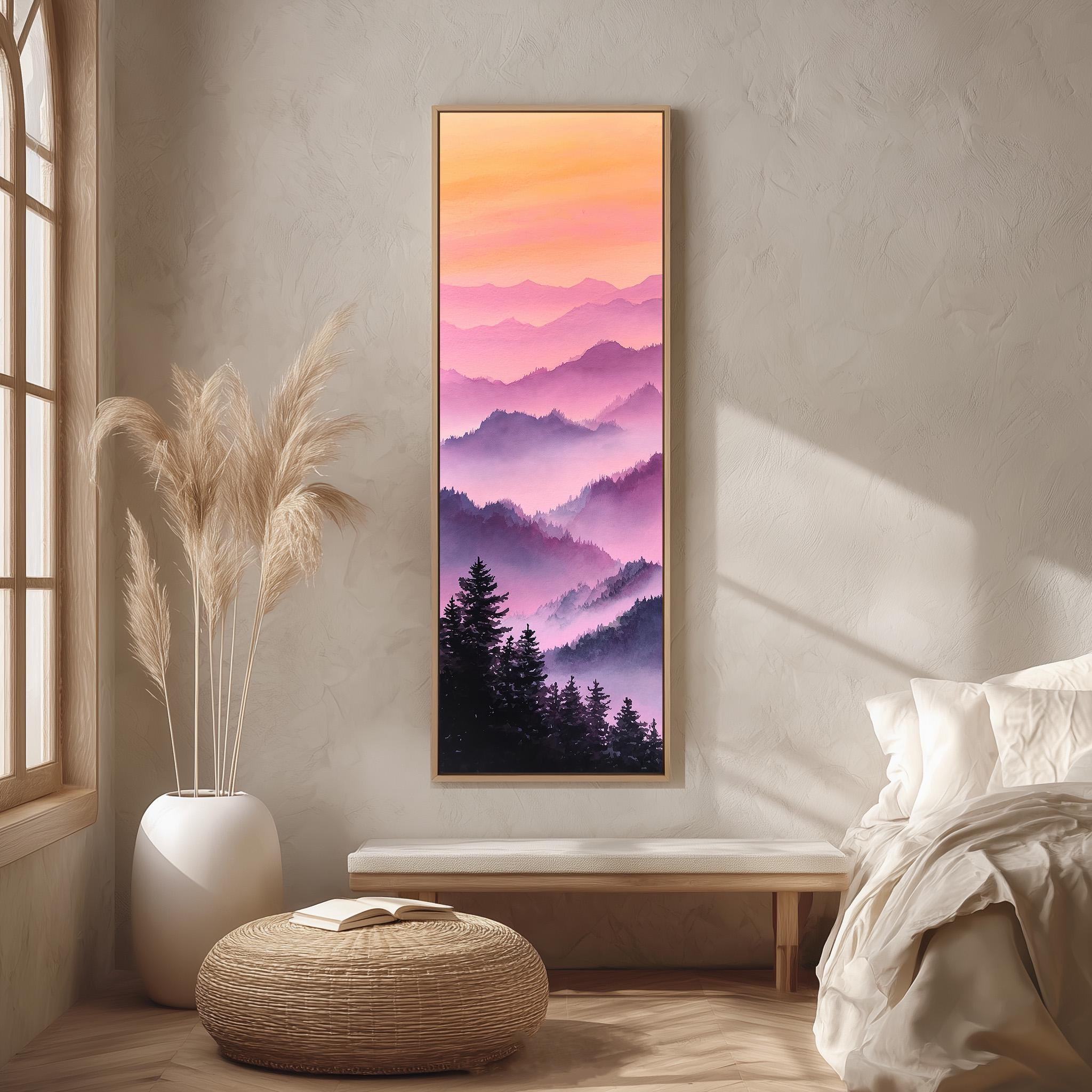 a serene bedroom scene with a large framed landscape painting hanging on the wall, depicting a mountain range at sunset. The painting is surrounded by a white bed, a wicker ottoman, and a potted plant, creating a cozy and inviting atmosphere.