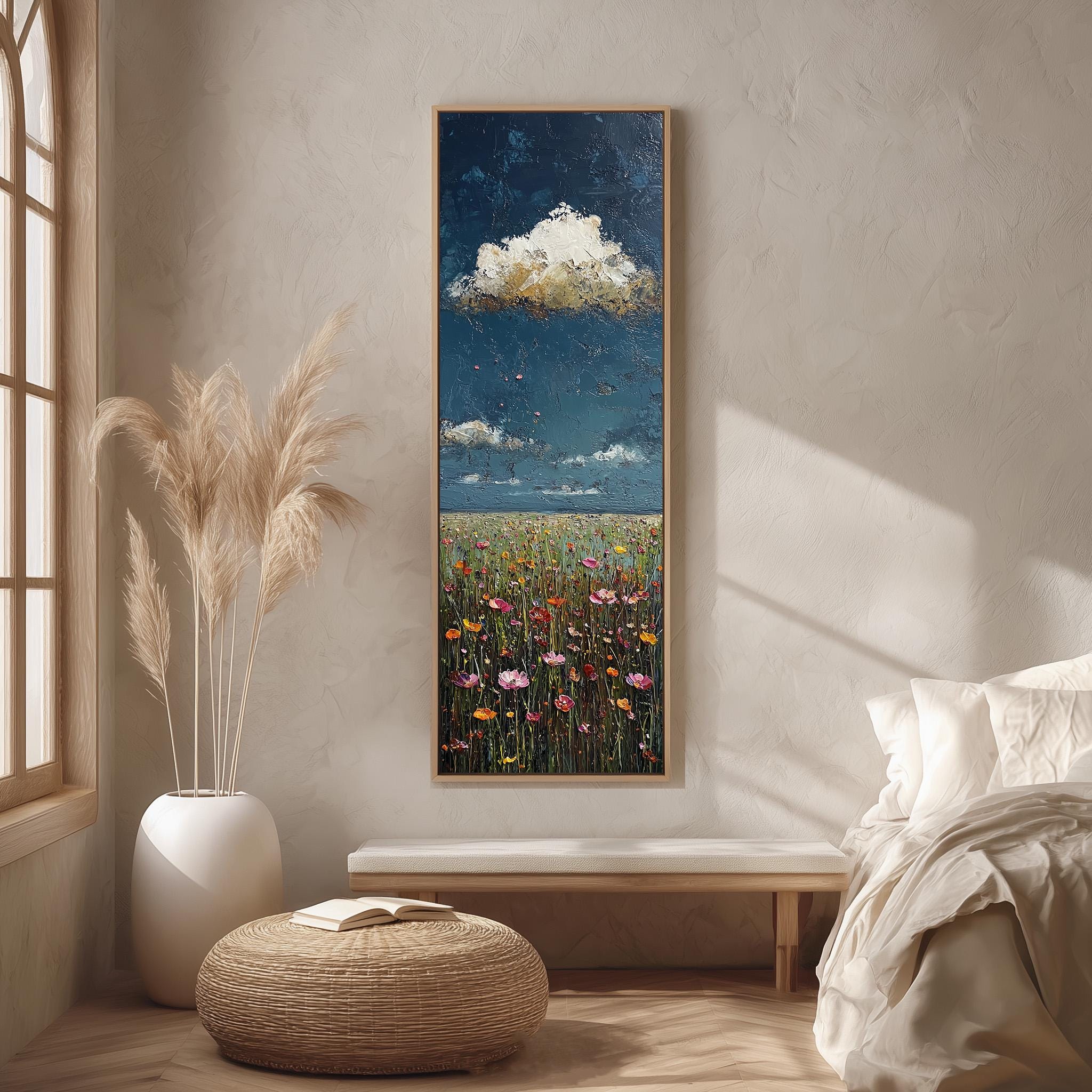 a serene bedroom scene with a large painting of a field of flowers hanging on the wall, a white bed with a white pillow, a white vase with tall potted plants, and a woven ottoman in front of the bed.