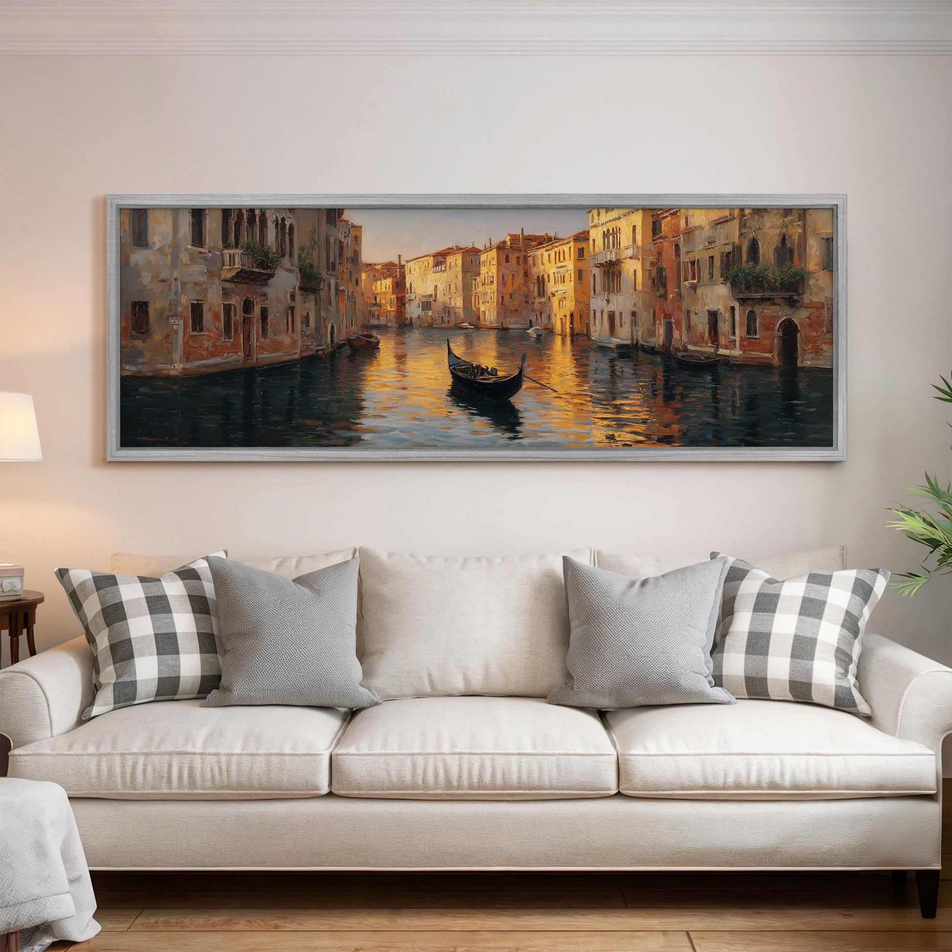 a large painting of a gondola on a canal, hanging on a wall above a white sofa with gray and white patterned pillows.