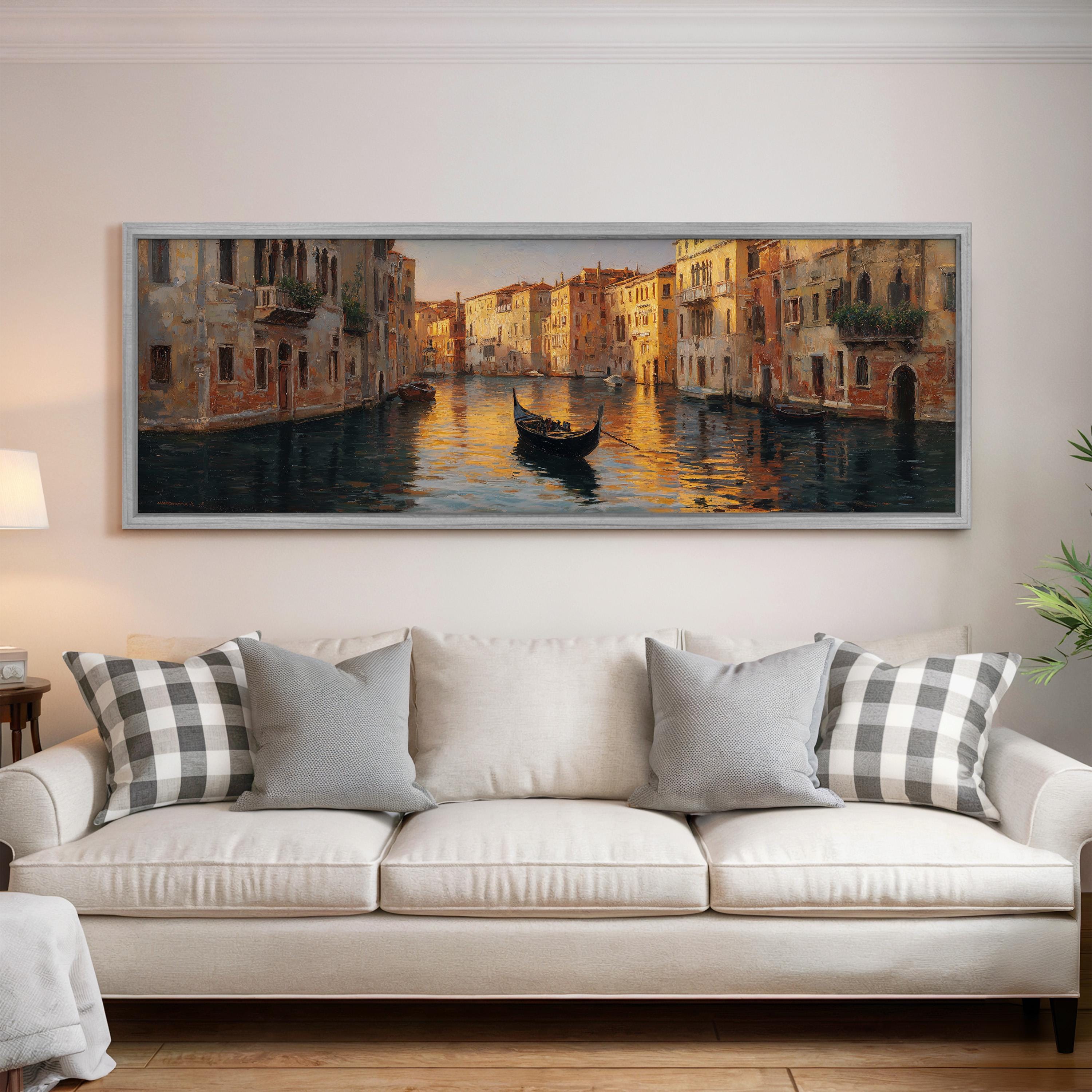 a large painting of a gondola on a canal, hanging on a wall above a white sofa with gray and white patterned pillows.