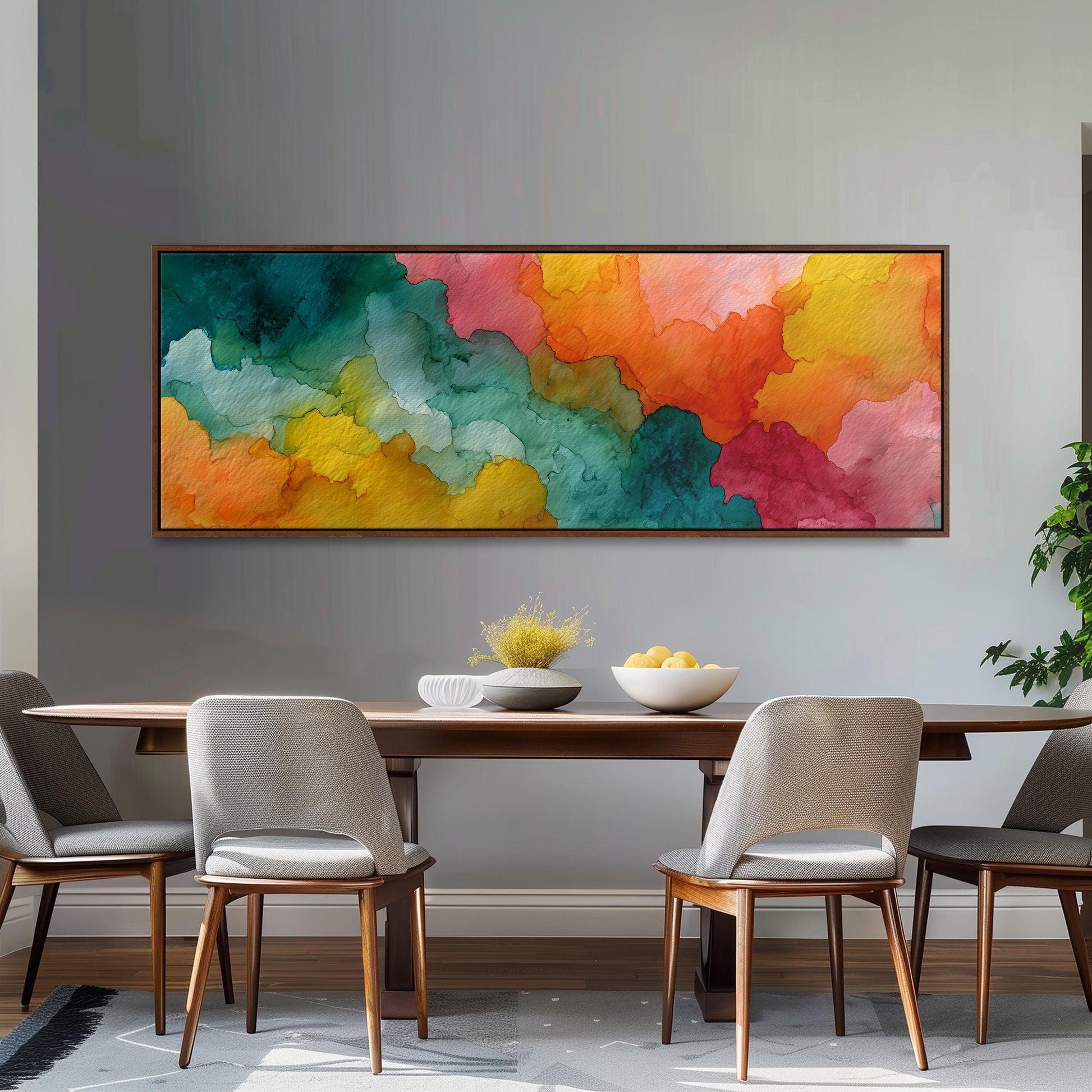 a dining room with a wooden table and four chairs. Above the table, there is a large, colorful abstract painting hanging on the wall. The painting has a vibrant mix of green, orange, yellow, and pink colors, creating a lively and energetic atmosphere in the room.