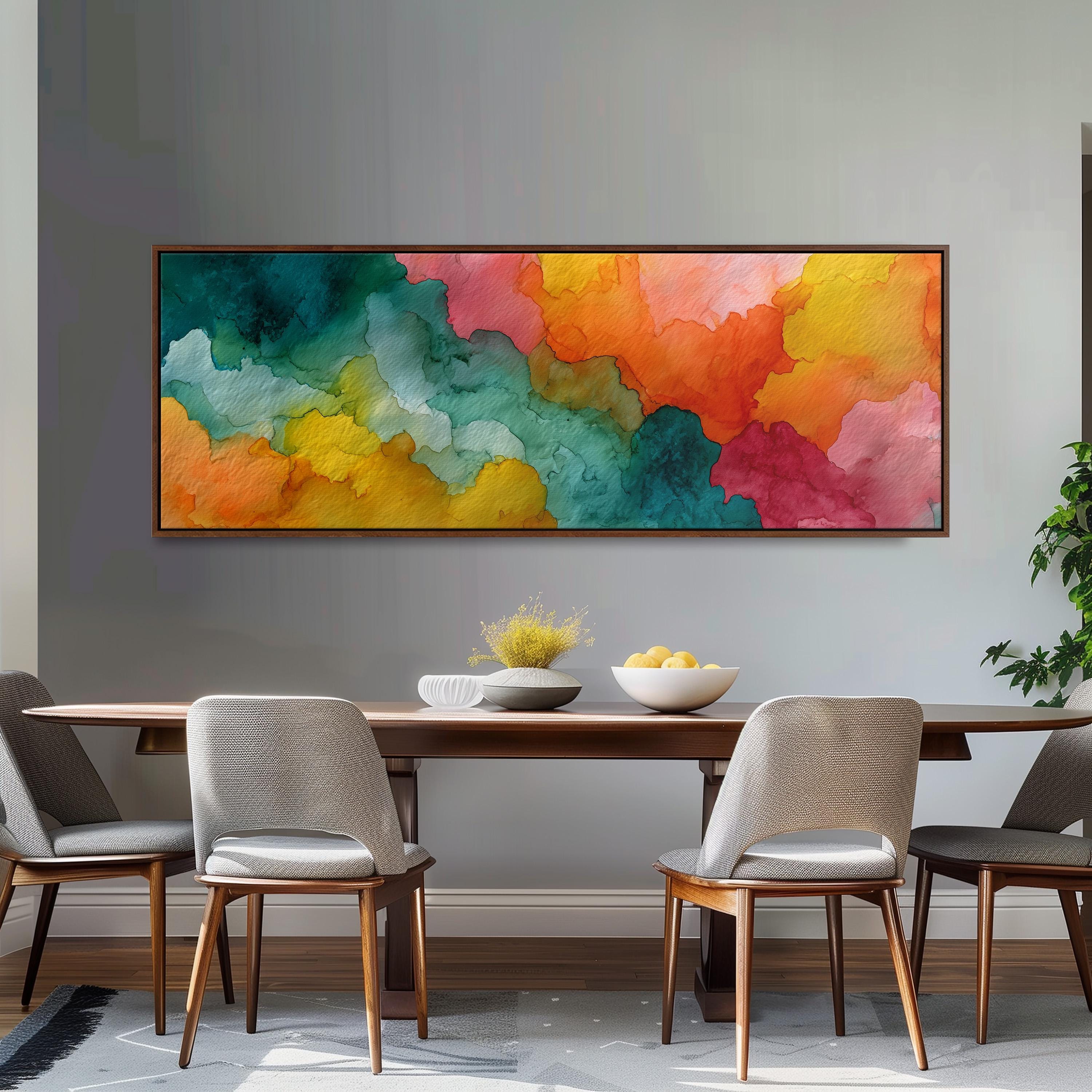 a dining room with a wooden table and four chairs. Above the table, there is a large, colorful abstract painting hanging on the wall. The painting has a vibrant mix of green, orange, yellow, and pink colors, creating a lively and energetic atmosphere in the room.