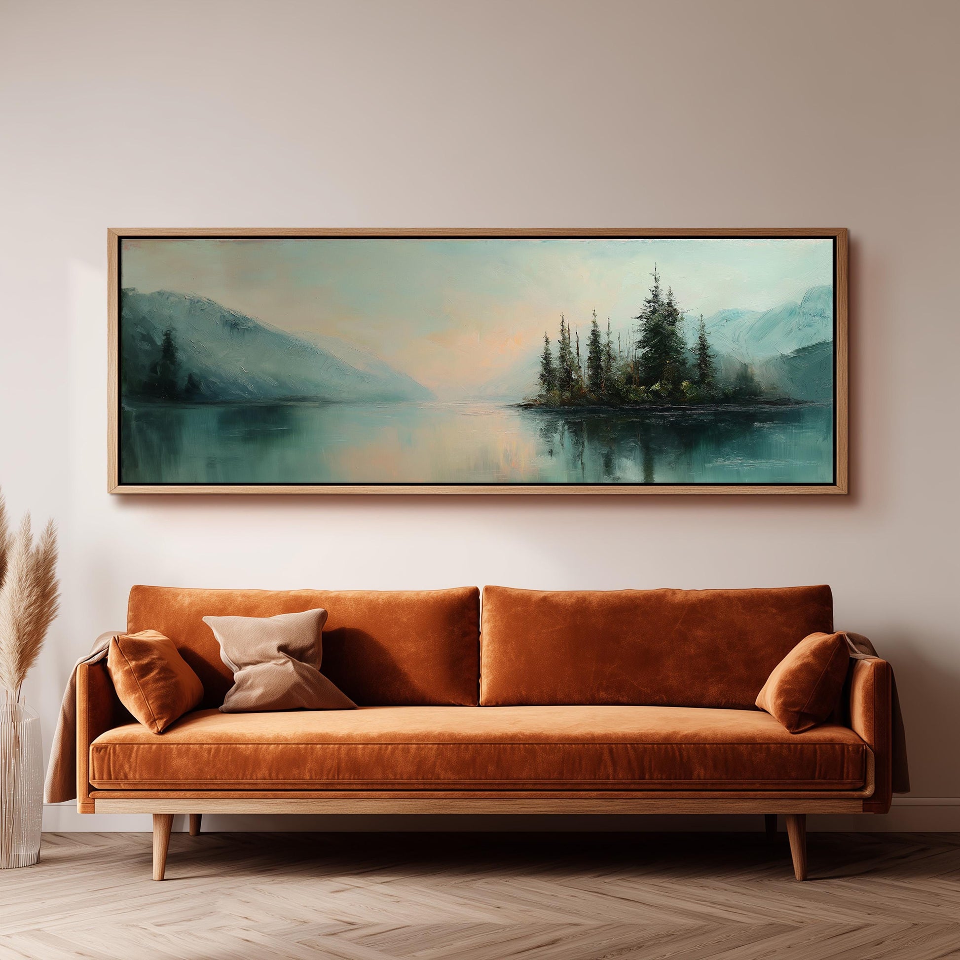a large painting of a serene landscape with a lake and mountains, hanging on a wall above a brown sofa with orange cushions.