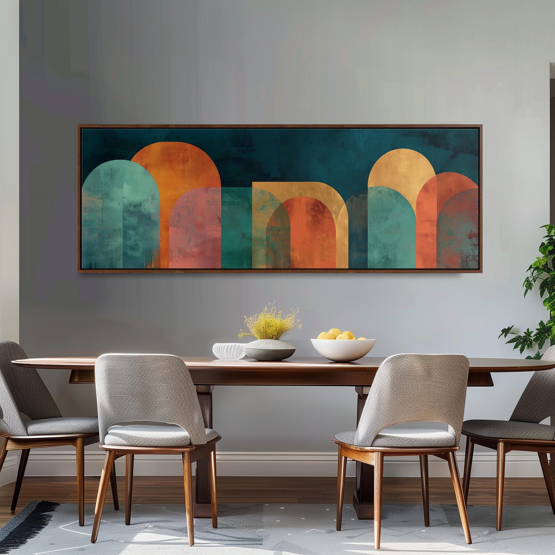 a modern dining room with a large abstract painting hanging on the wall above a wooden dining table with four chairs. The table is set with a bowl of fruit and a vase of flowers, creating a welcoming and stylish atmosphere.