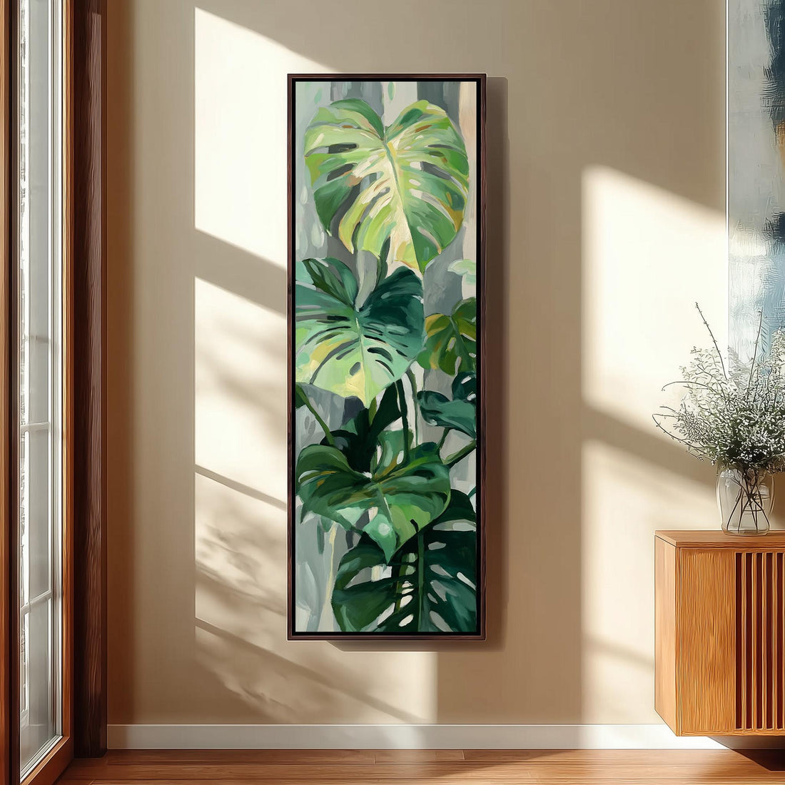 a large painting of a tropical plant hanging on a wall in a room with a wooden cabinet and a vase of flowers.