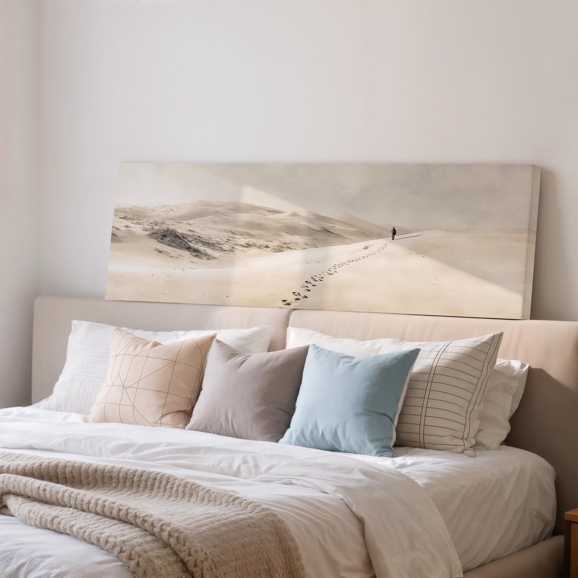 a cozy bedroom scene with a large bed adorned with white linens and a variety of colorful pillows. Above the bed, there is a framed print depicting a snowy mountain landscape with a lone figure walking along a path.