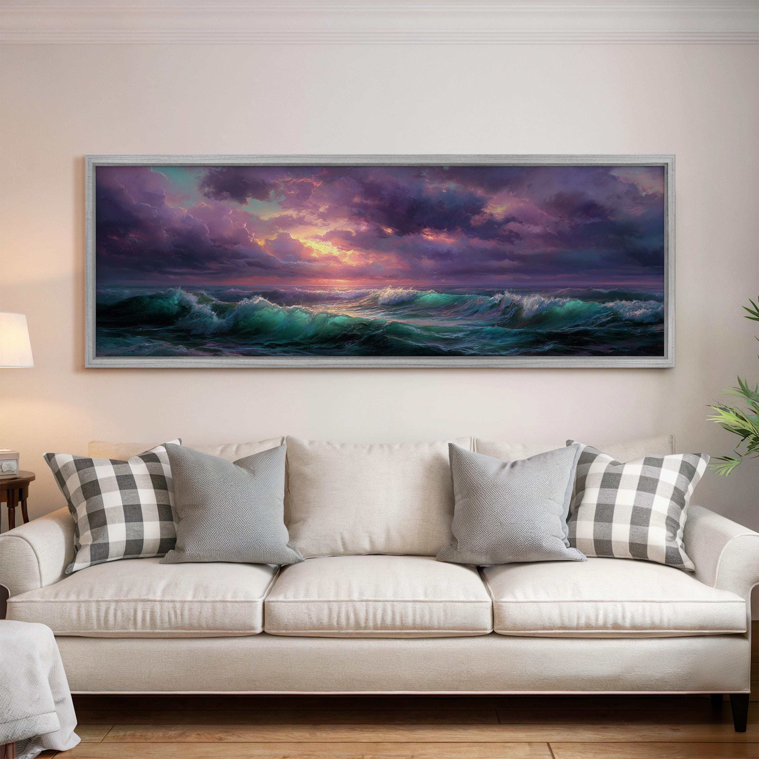a large, framed painting of a seascape hanging on a wall above a white sofa with gray and white patterned throw pillows.