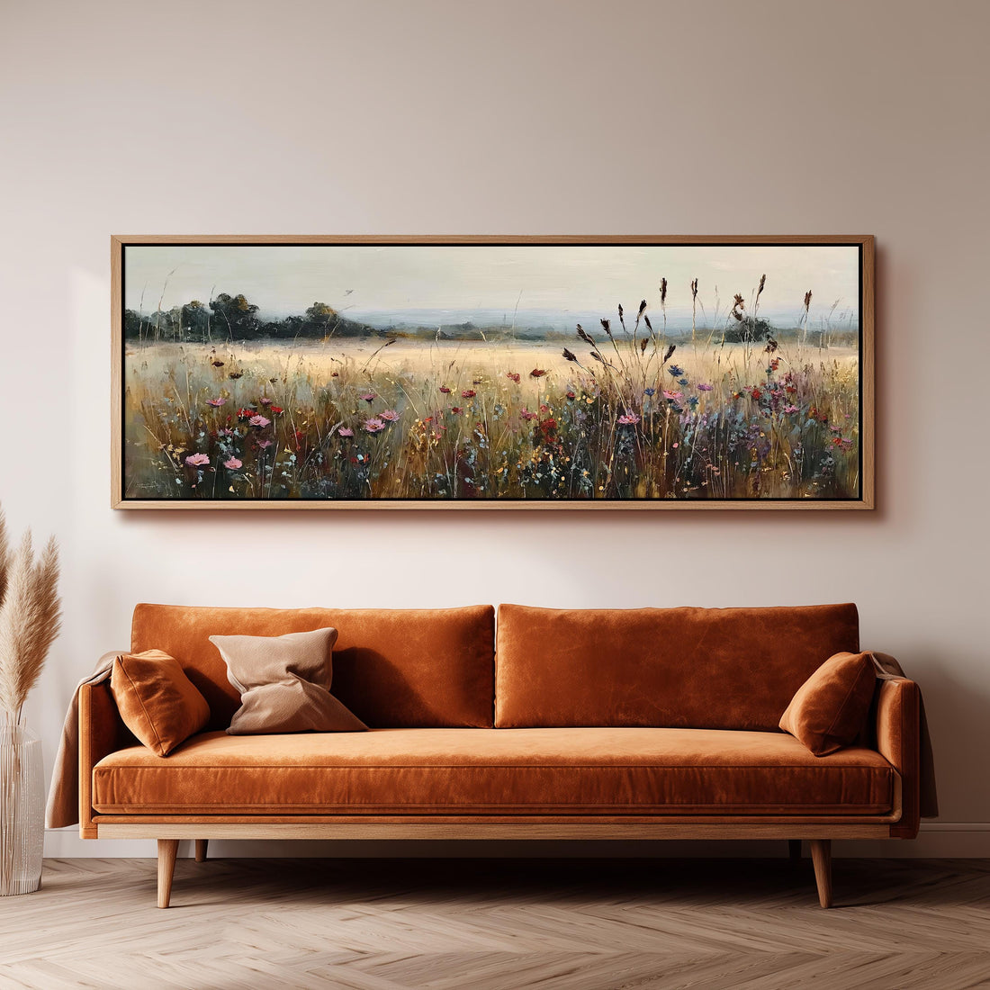 a large, framed painting of a field with flowers hanging on a wall above a brown sofa.
