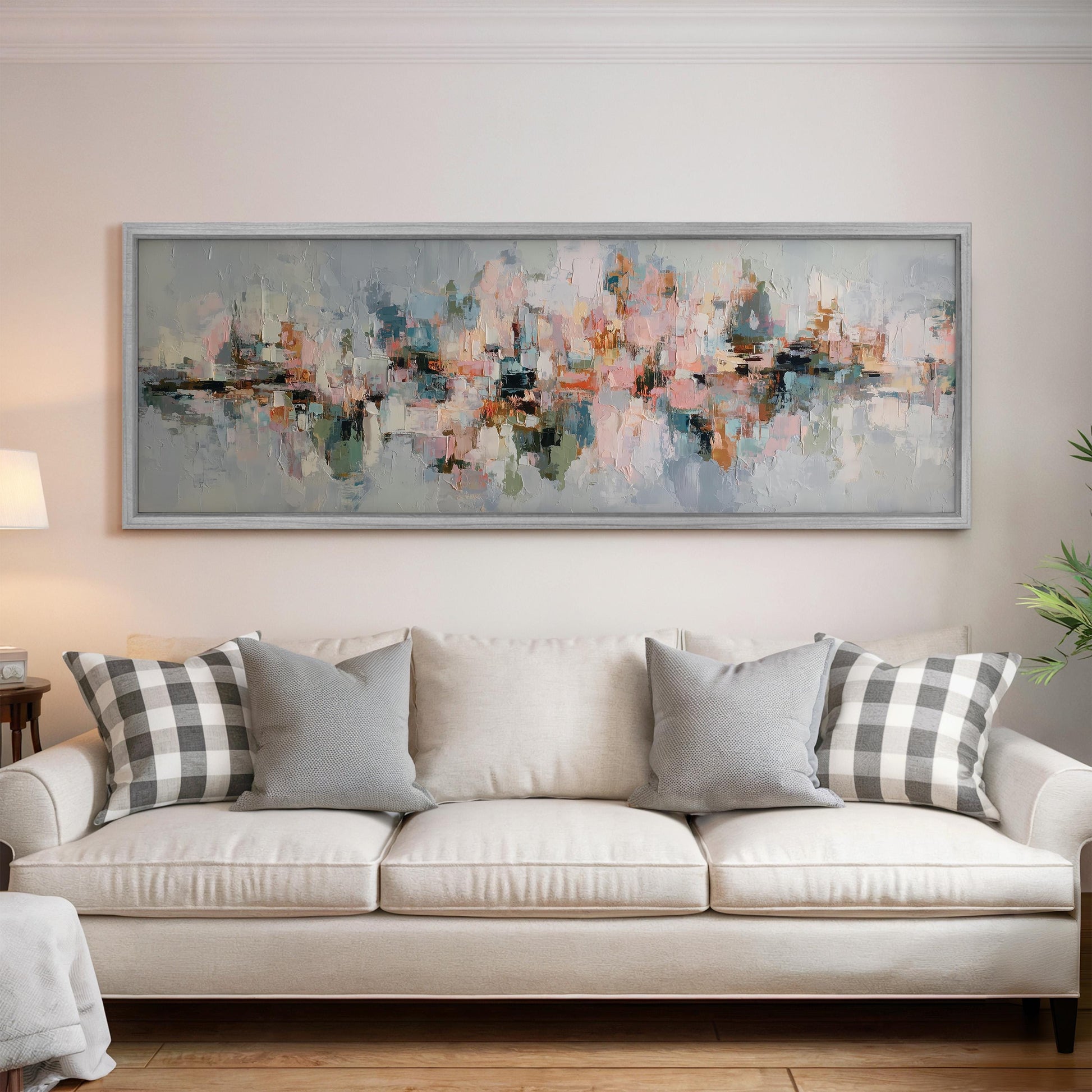a large, abstract painting hanging on a wall above a white sofa with gray and black plaid throw pillows.