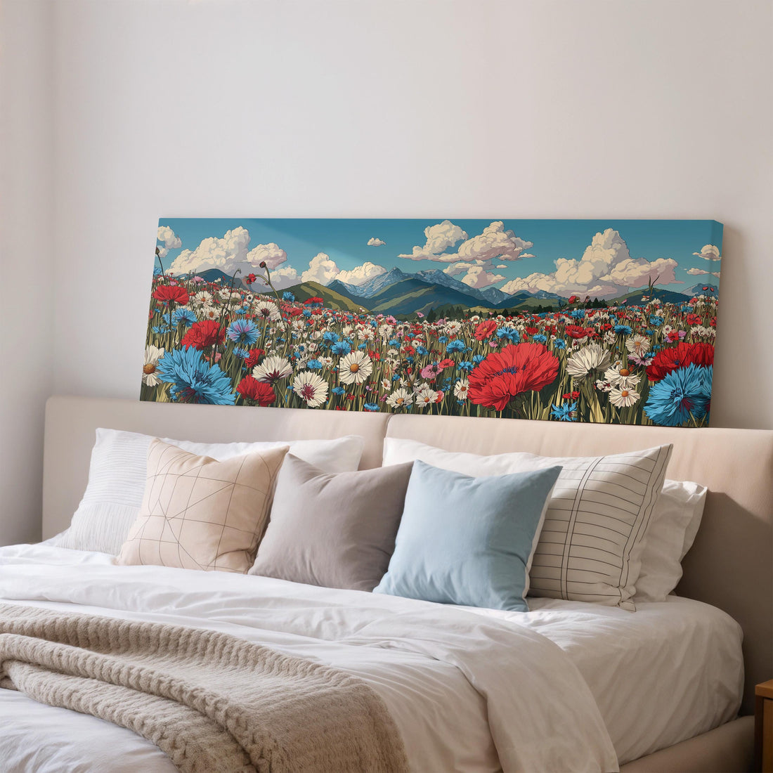 a large canvas print of a colorful field of flowers hanging above a bed with white pillows and a gray blanket.