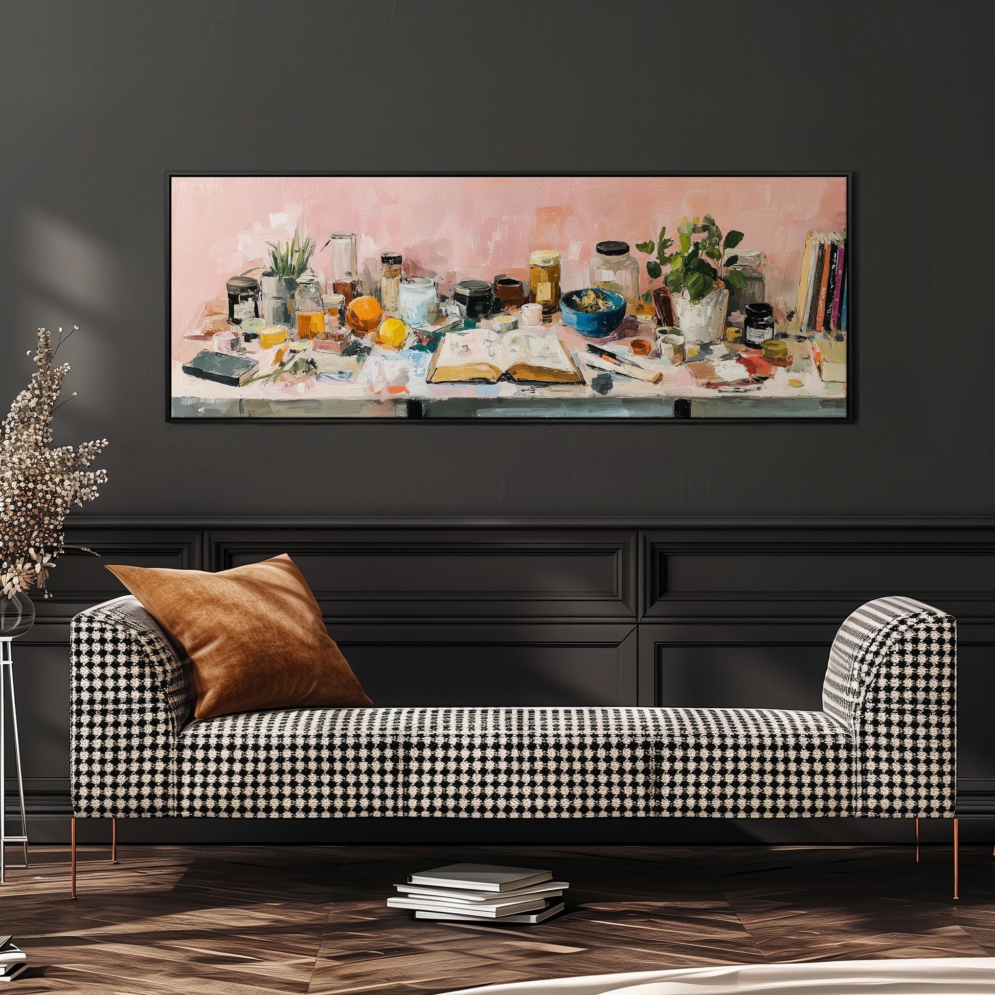a checkered sofa with a stack of books on the floor in front of it, and a large painting of various objects displayed on a wall above the sofa.