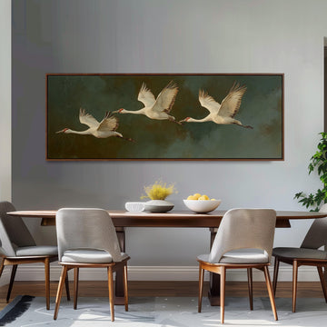 a dining room with a large painting of three white birds in flight above a wooden table. The table is set with a bowl of fruit and a vase of flowers, creating a cozy and inviting atmosphere.