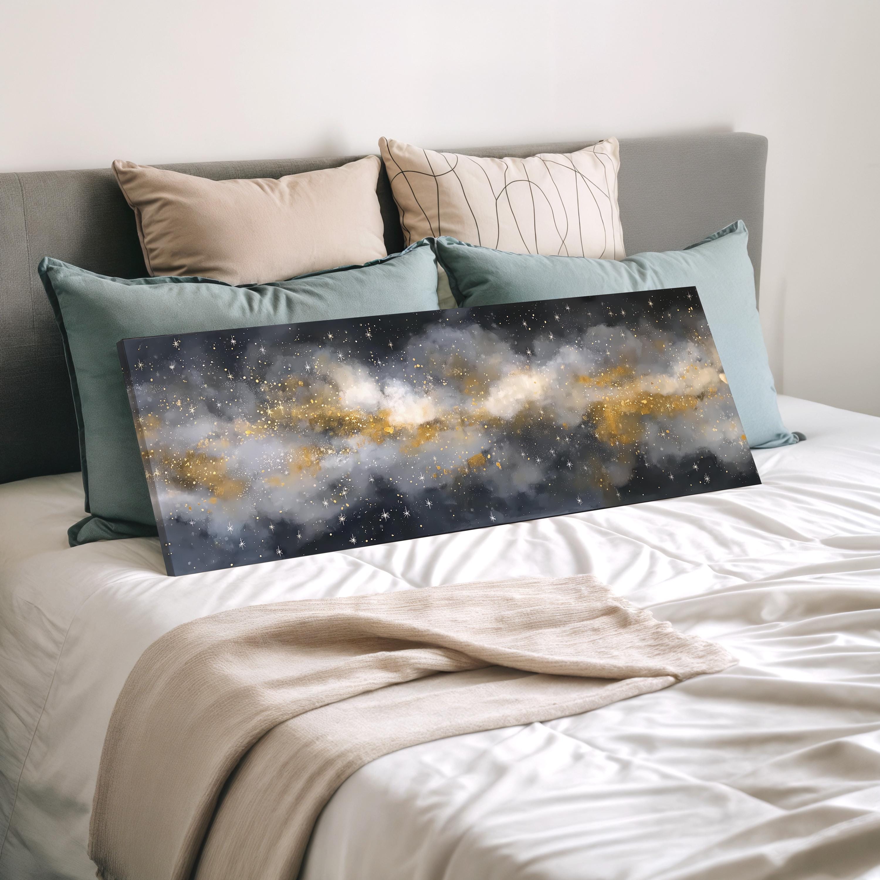 a bedroom with a bed covered in white sheets and a large canvas print of a starry night sky displayed on the bed.