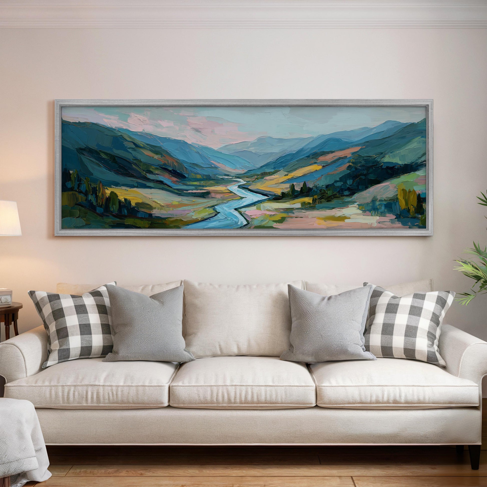 a large, colorful landscape painting hanging on a wall above a white couch with gray and white patterned pillows.
